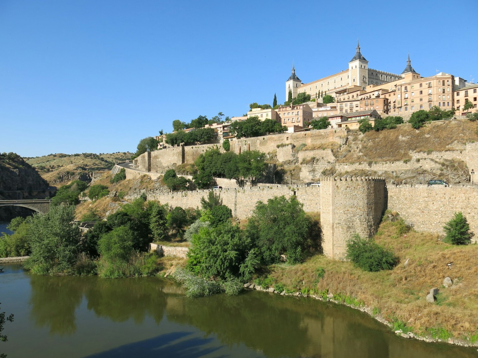 Malersiche Aussicht auf Toledos historische Mauern und das Alcázar unter klarem blauen Himmel