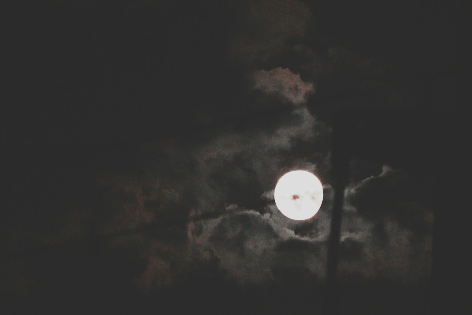 Bright moon against a dark sky with scattered clouds