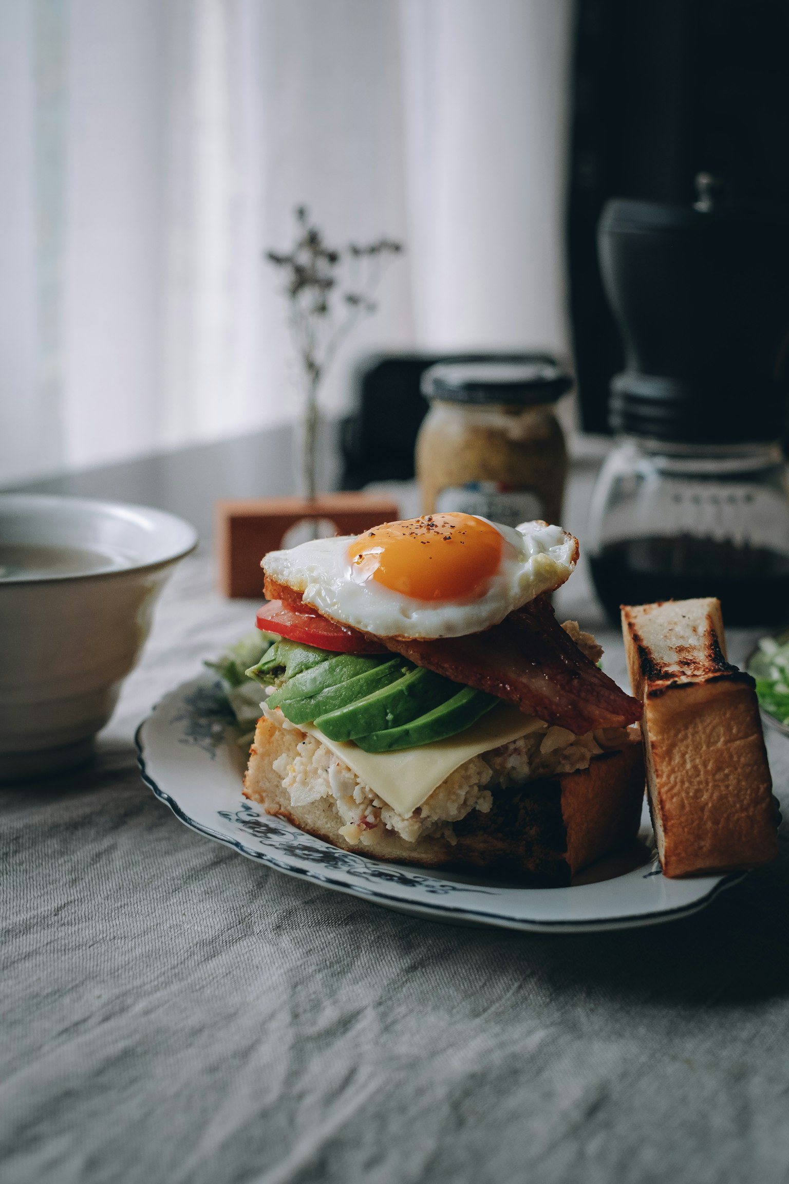 A food photo featuring toast topped with a fried egg, lettuce, and tomato