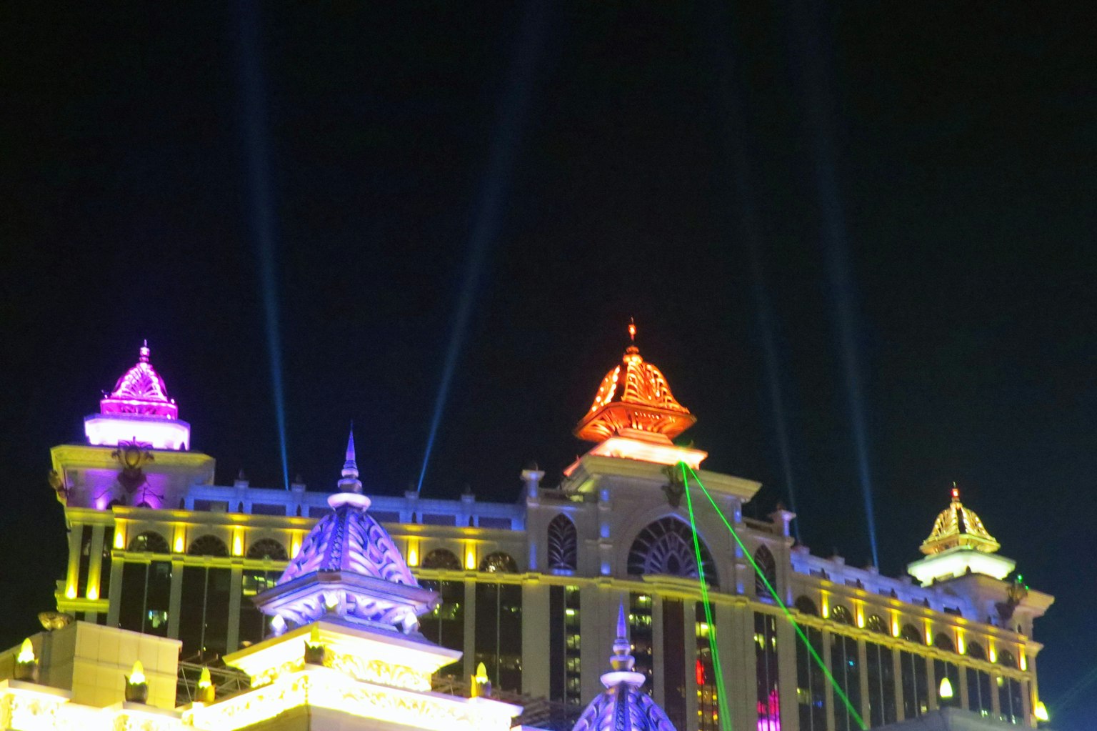 Lumières colorées et faisceaux illuminant les toits d'un bâtiment magnifique la nuit