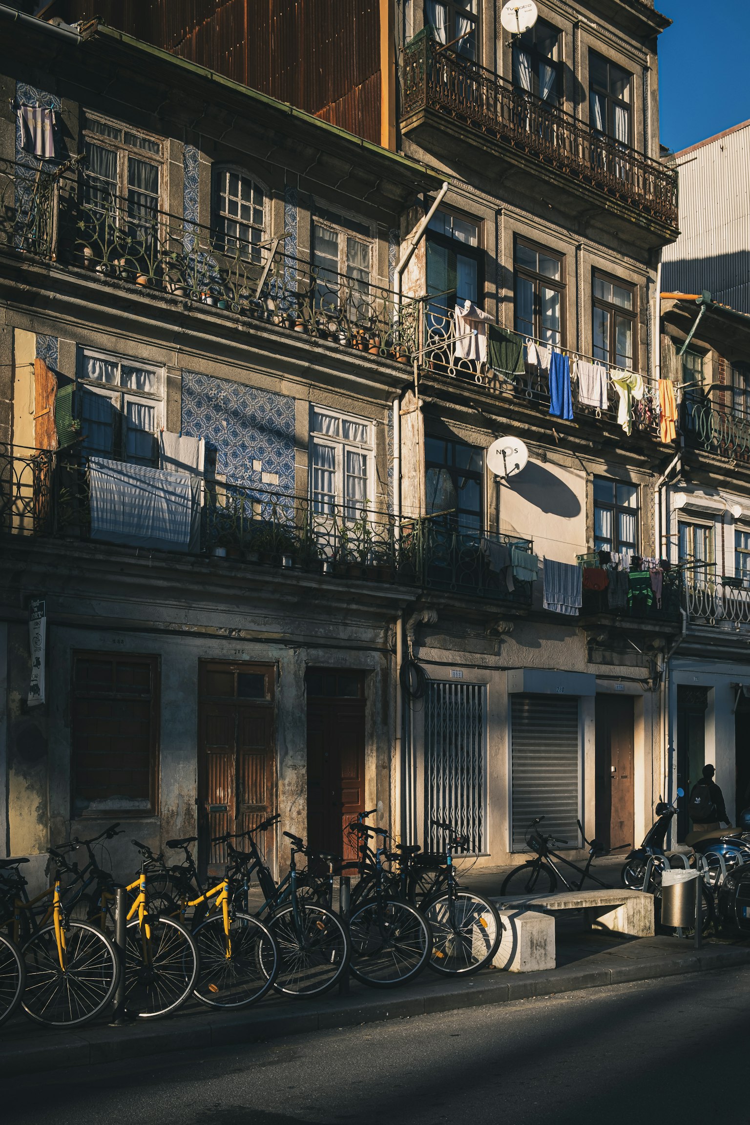 Extérieur d'un vieux bâtiment avec des vélos garés devant du linge suspendu sur les balcons lumière du soleil illuminant la rue