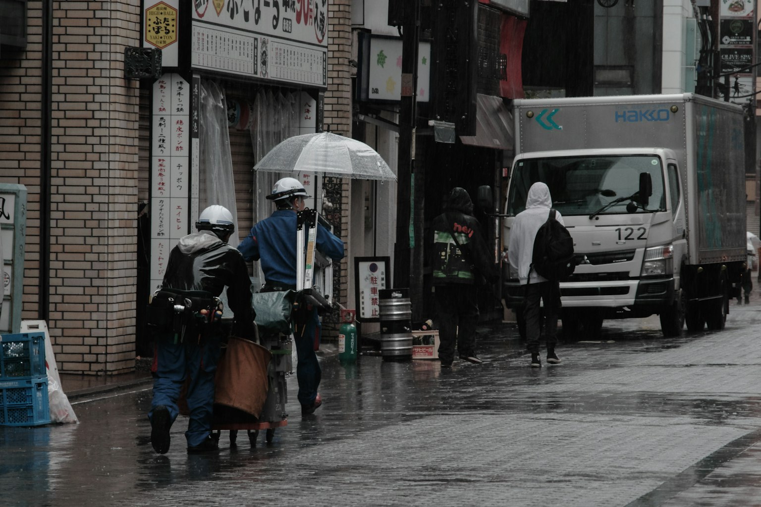 Workers walking on a rainy street with an umbrella