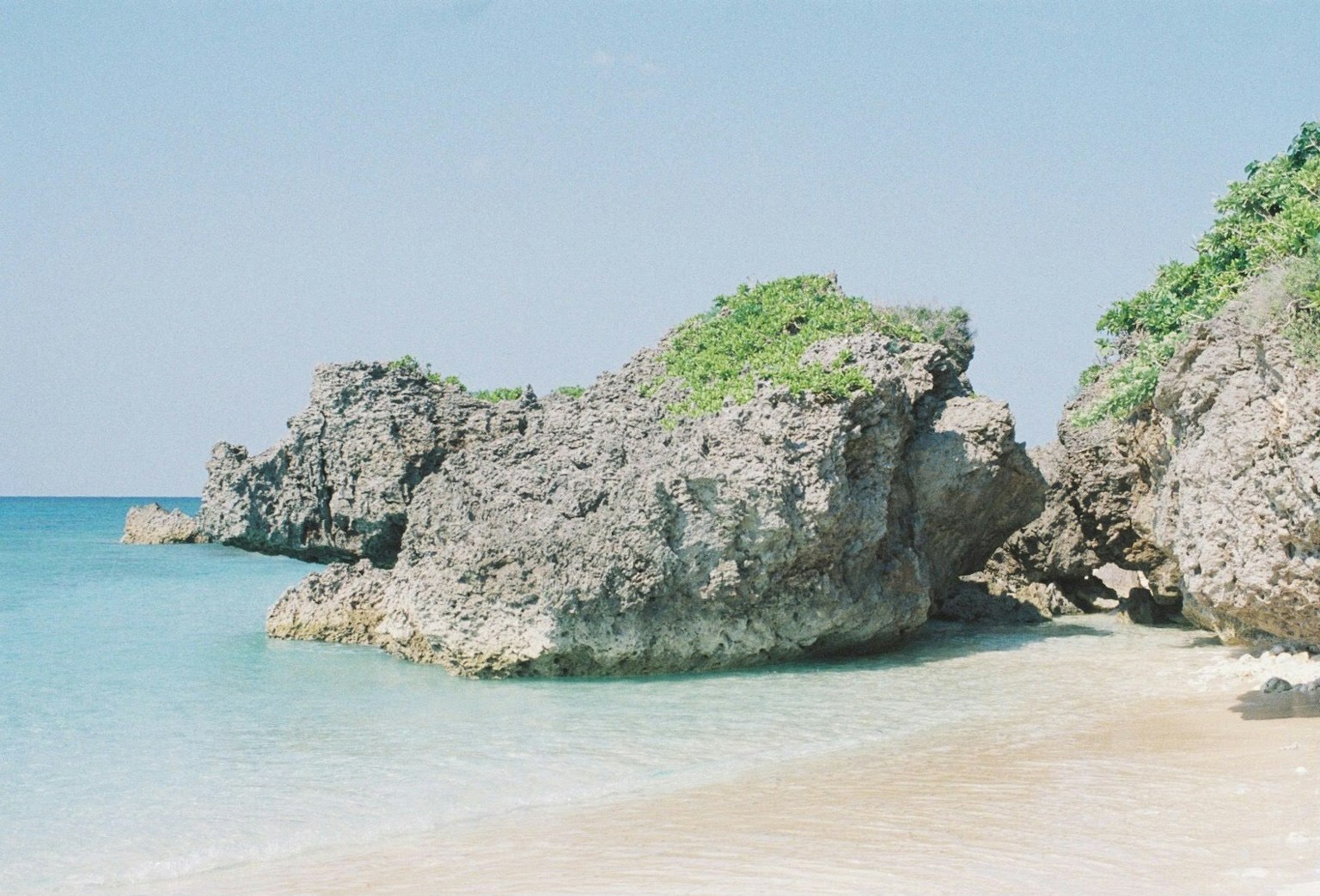 Escena de playa con agua azul y formaciones rocosas