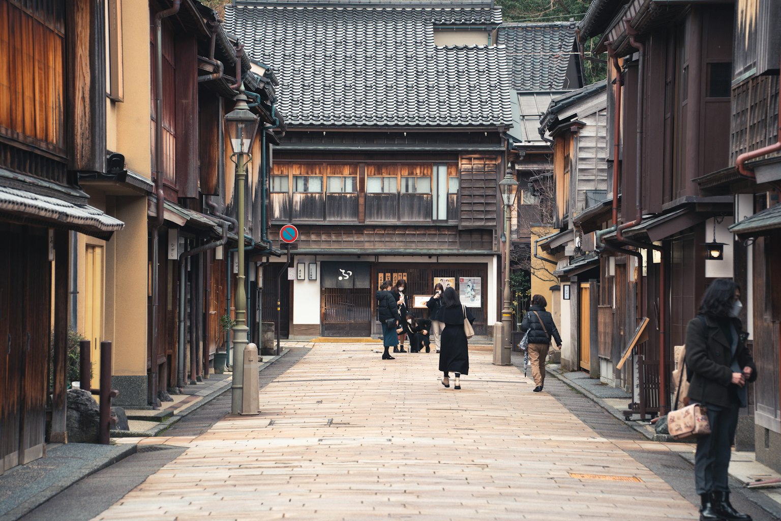 A quiet street lined with traditional wooden buildings and people walking