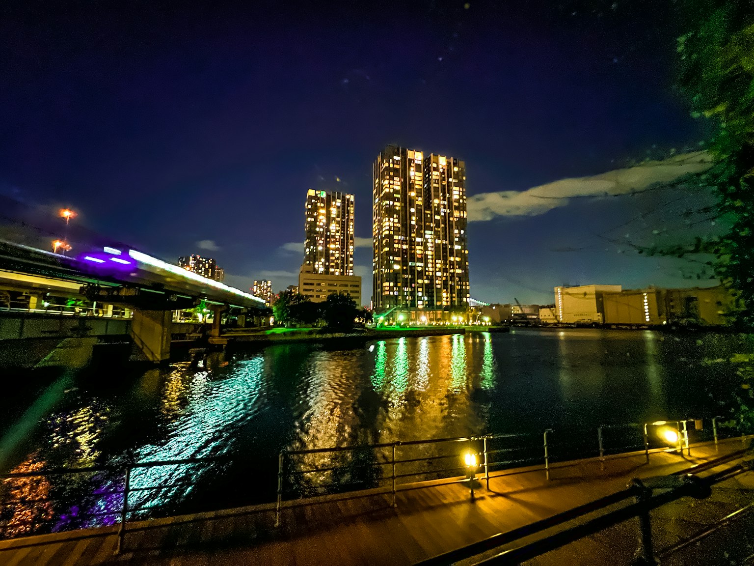 Paisaje urbano nocturno con rascacielos iluminados reflejándose en el agua