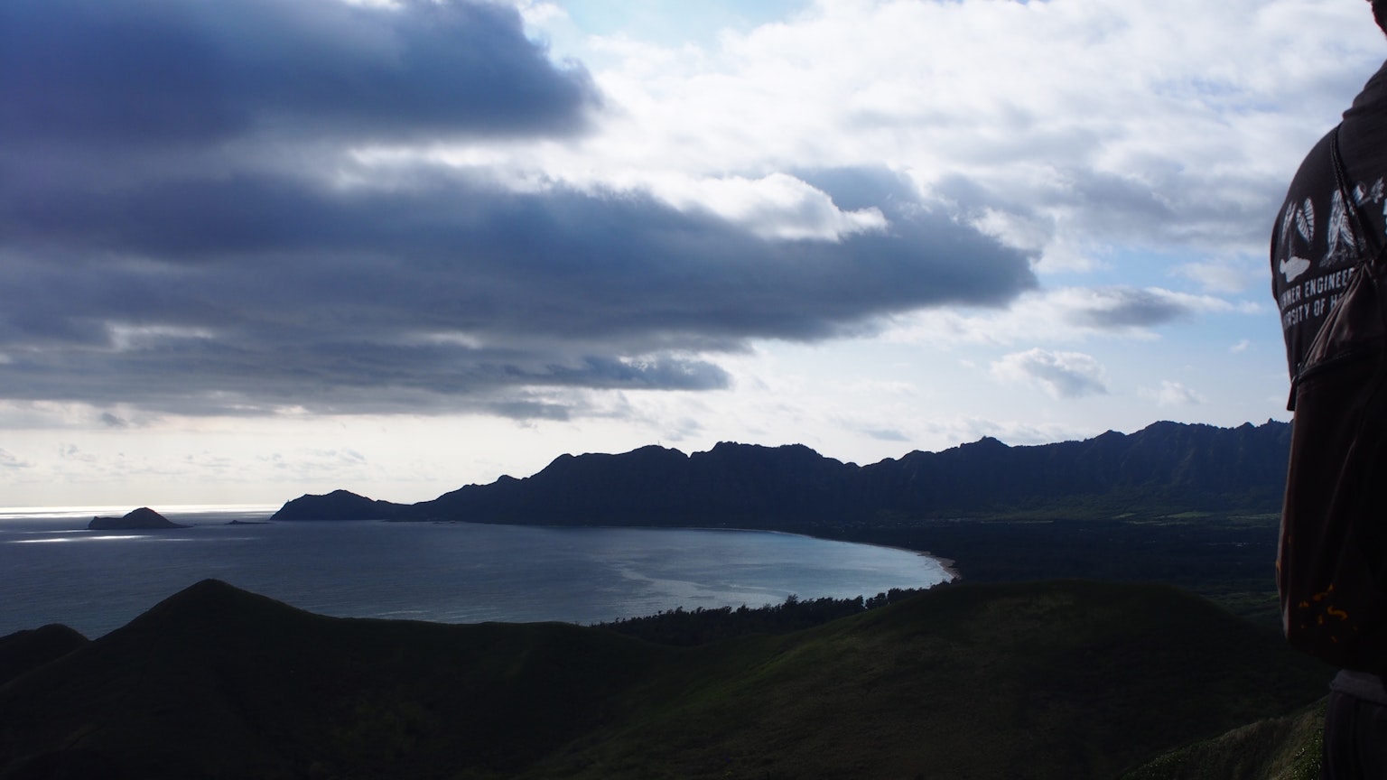 Pemandangan pegunungan dan pantai di bawah langit mendung