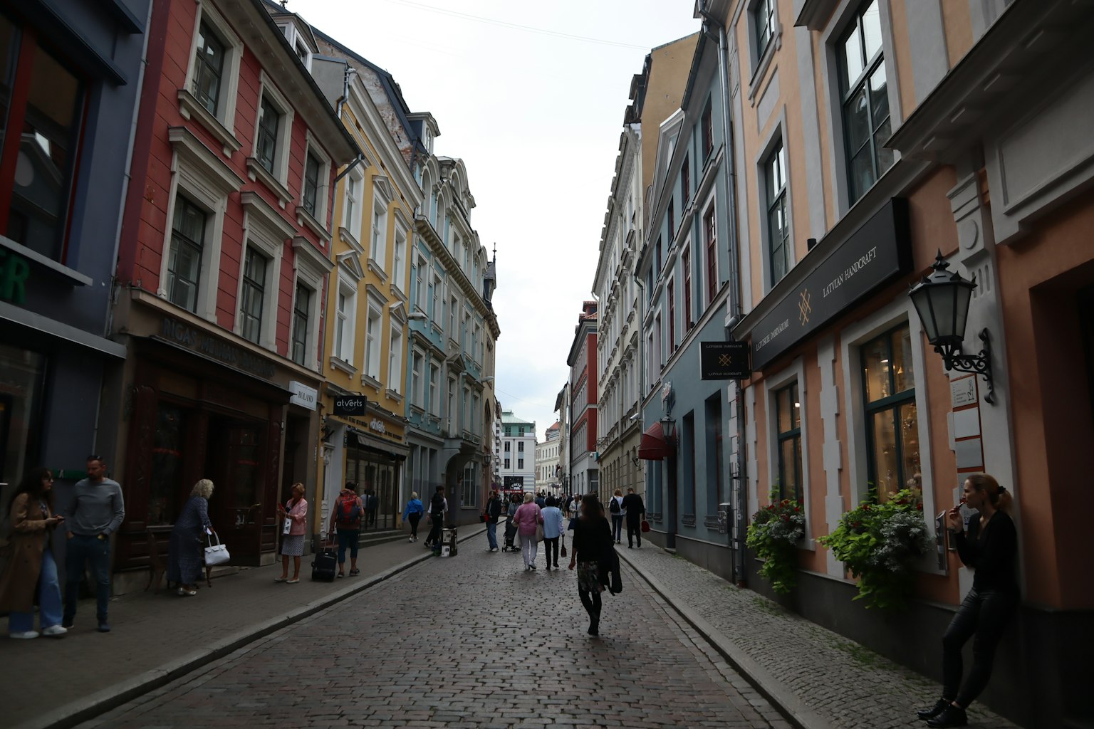 Bunte Gebäude säumen eine Straße mit Menschen, die auf Kopfsteinpflaster gehen