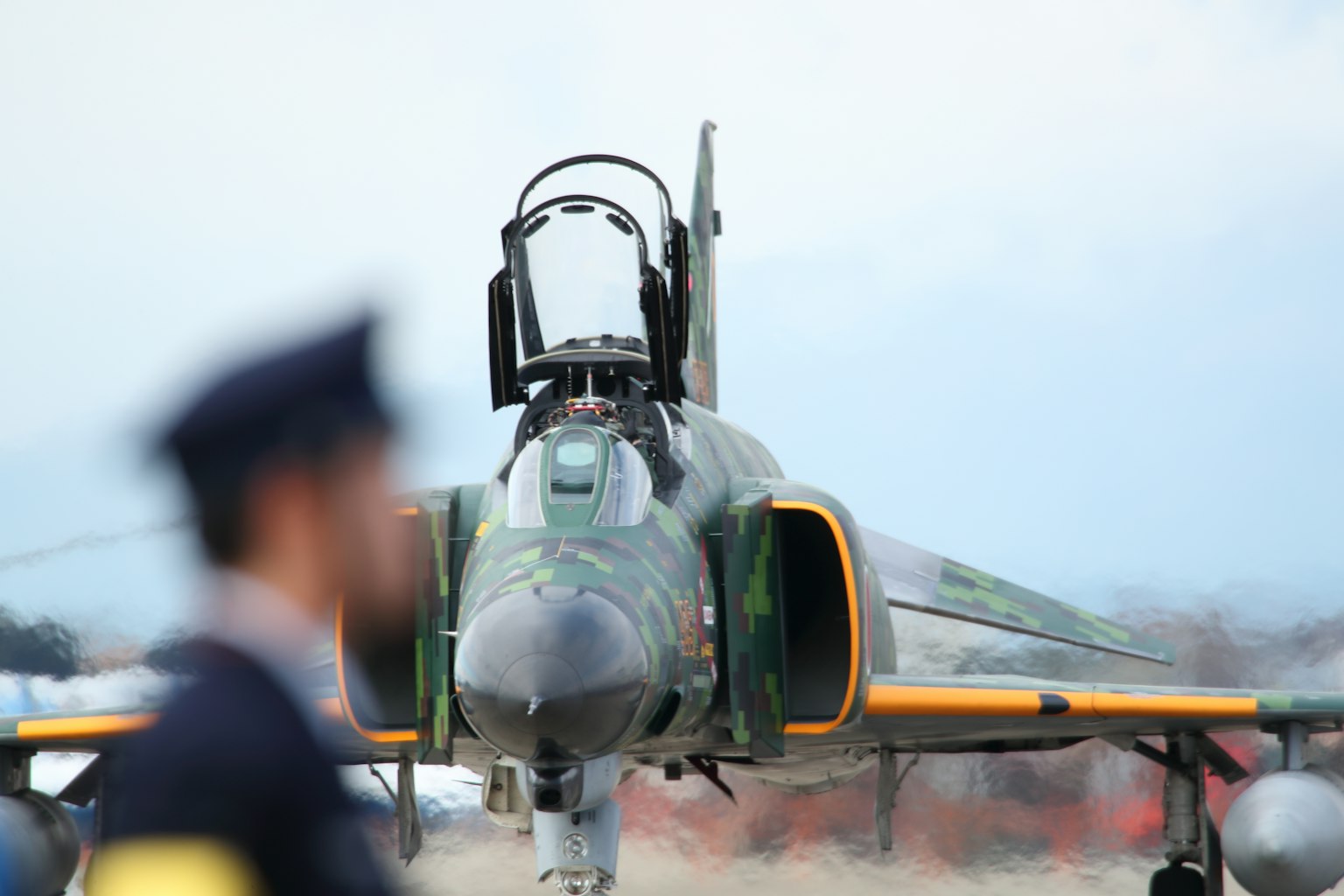 Gambar jet tempur F-4 Phantom di pertunjukan udara dengan sosok buram di latar depan