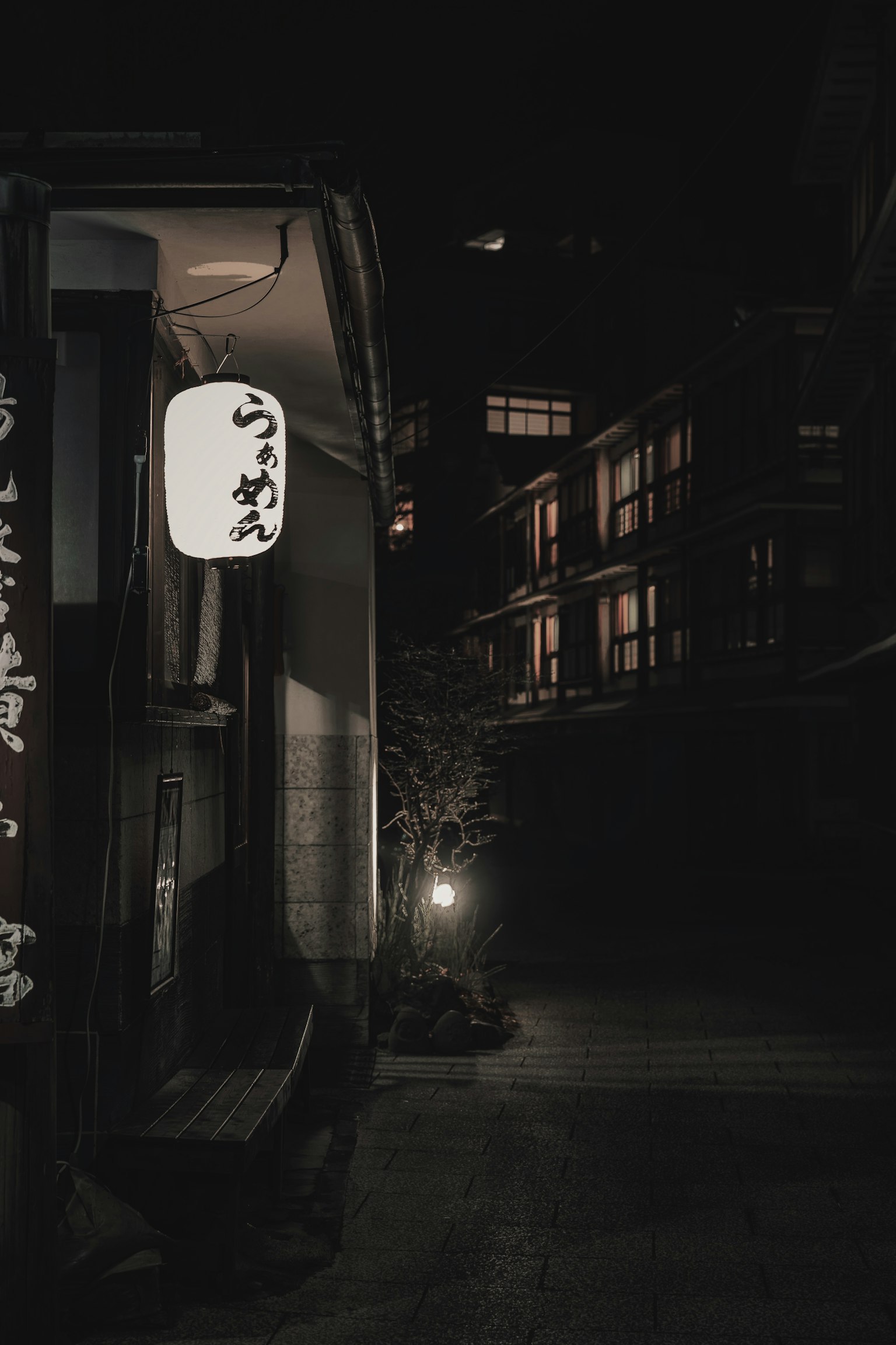 Straßenecke bei Nacht mit einer Laterne und einer dunklen Gasse