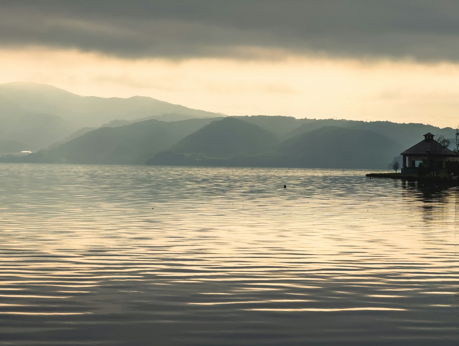 Ruhige Seesicht mit Bergen und bewölktem Himmel