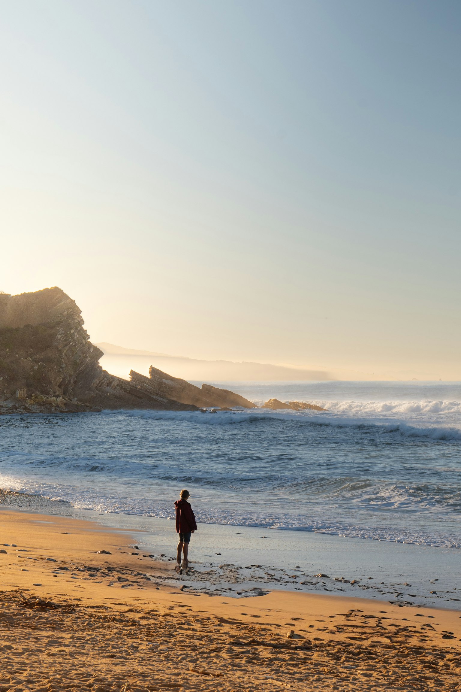 海滩上站着的人与波浪和岩石海岸