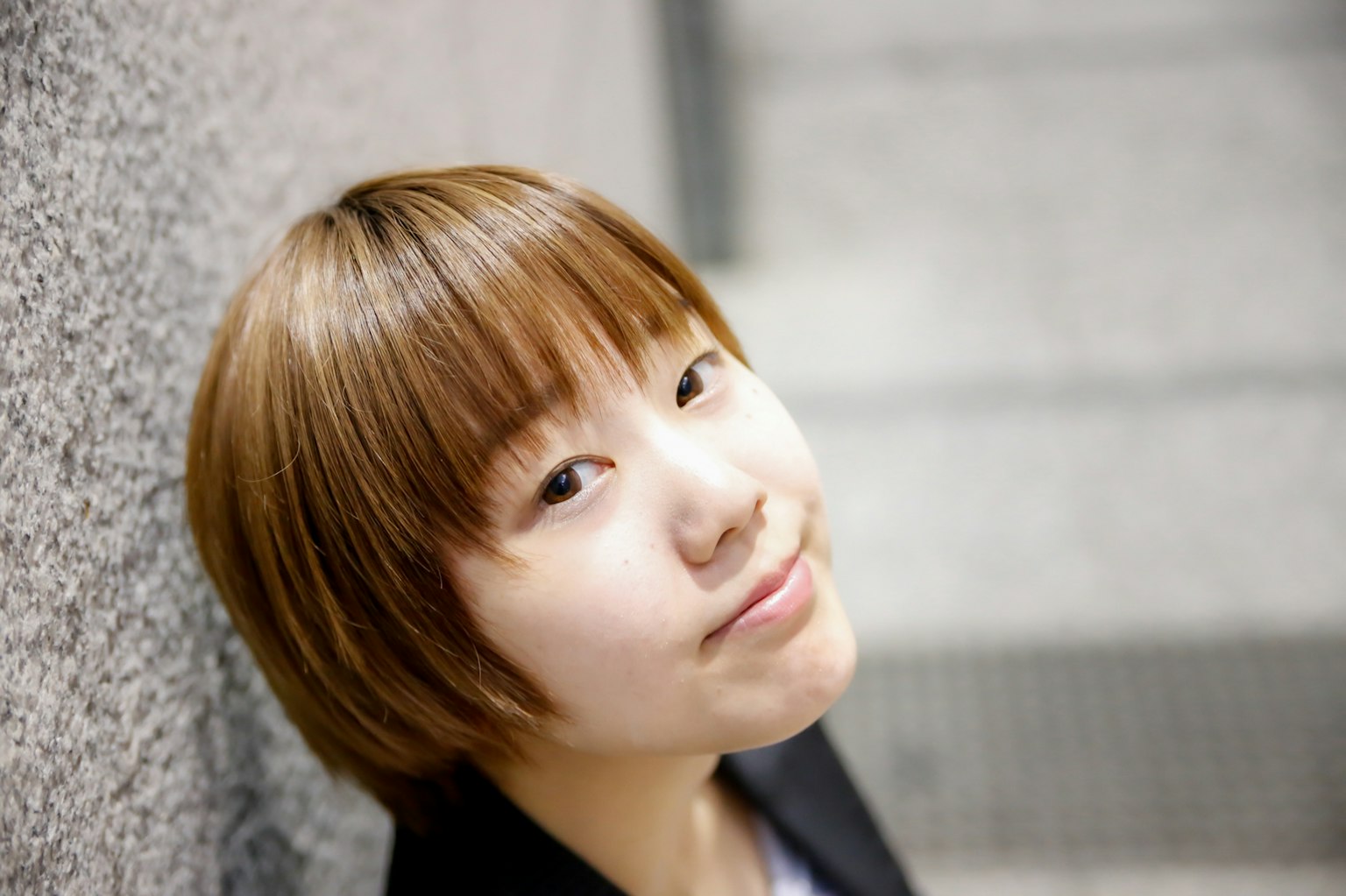 Portrait d'une jeune femme souriante adossée à un mur
