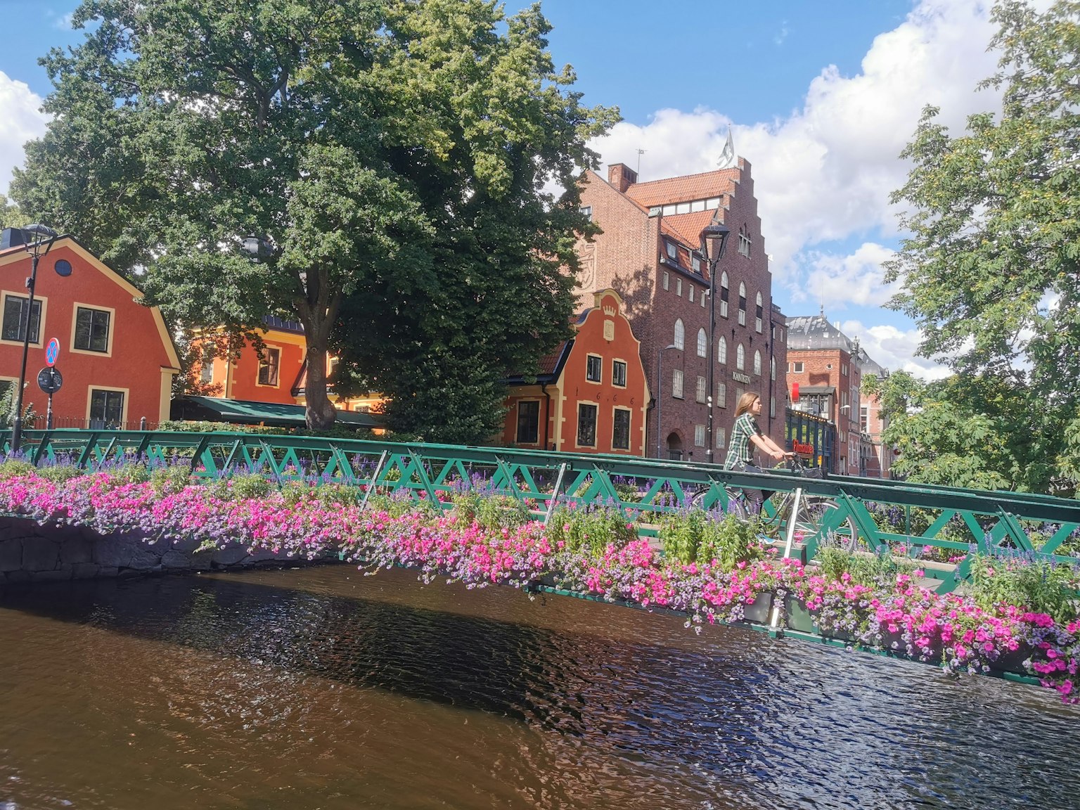 Malersicher Blick auf einen Fluss mit einer blumenverzierten Brücke historische Gebäude im Hintergrund