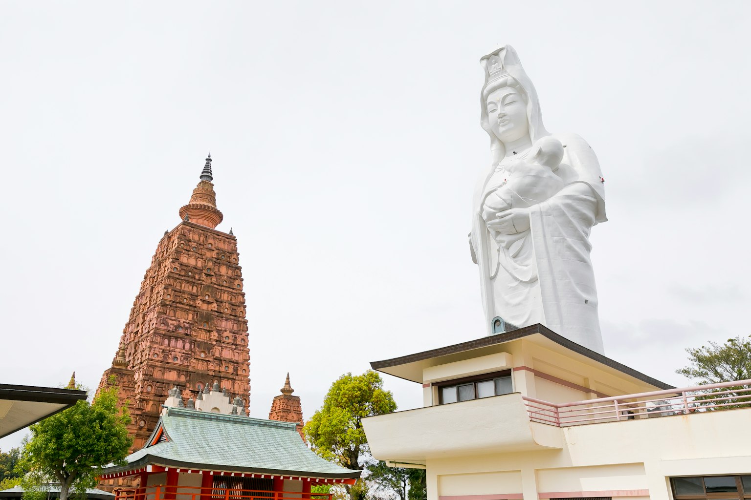 Grande statue de Kuan Yin à côté d'un ancien temple