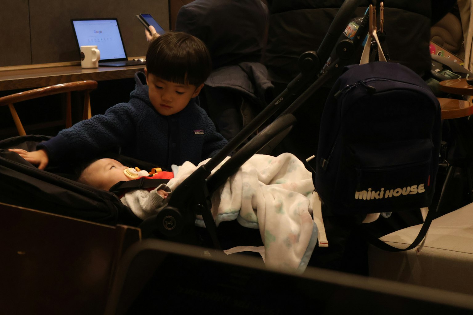 子供がベビーカーの赤ちゃんに触れているカフェのシーン