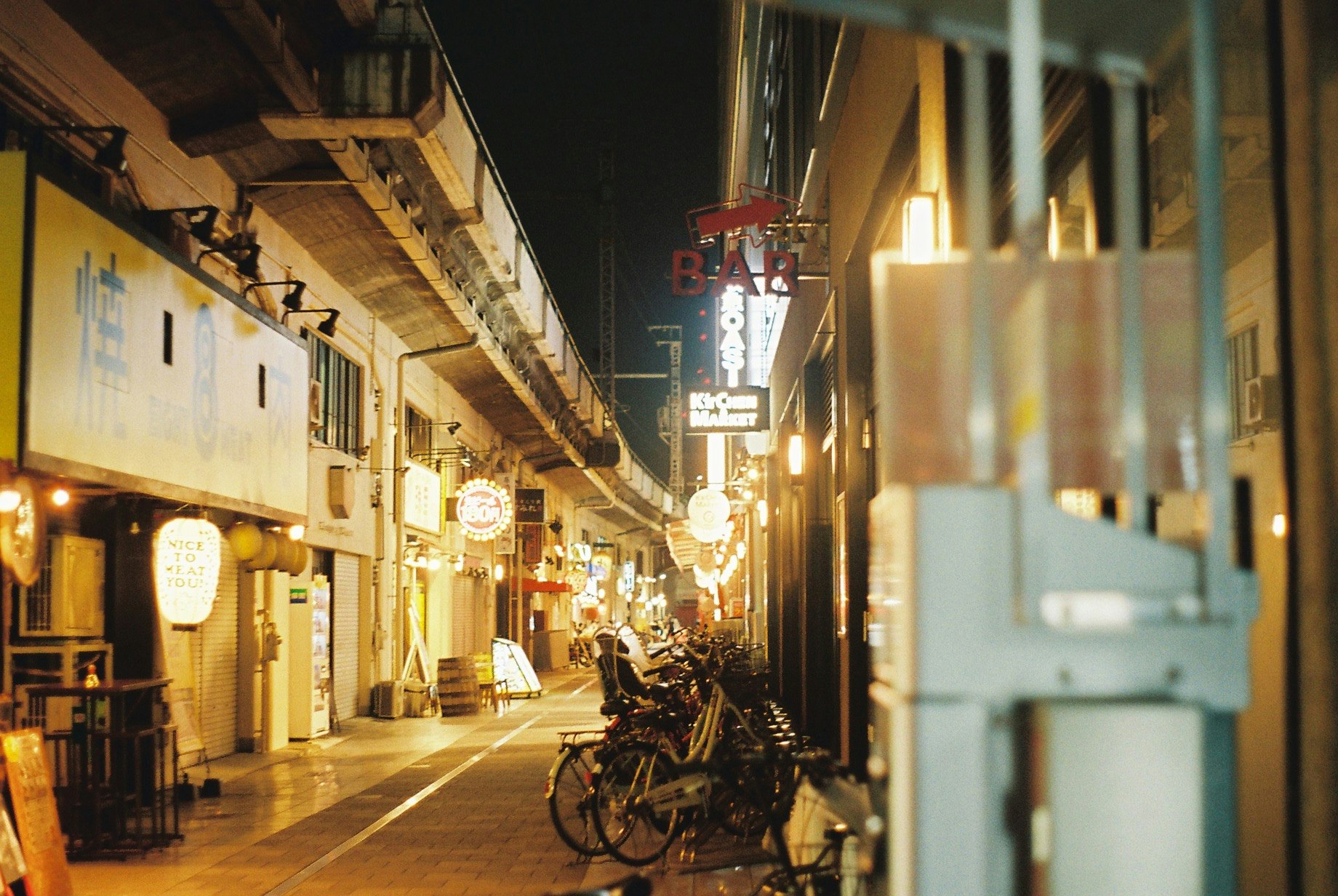 高架下の飲屋街で自転車が並ぶ夜の路地