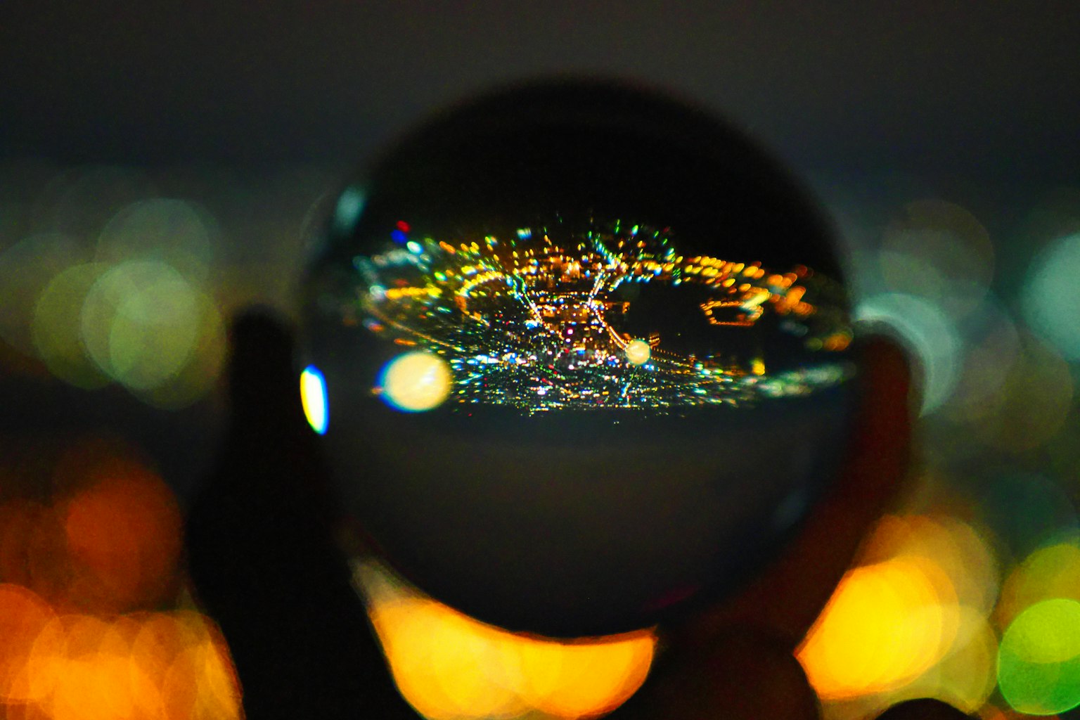 Una sfera di cristallo tenuta in mano che riflette un bellissimo paesaggio notturno cittadino