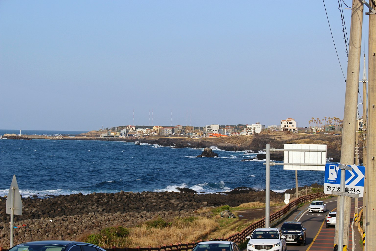 Coastal road view with blue ocean houses and scattered rocks