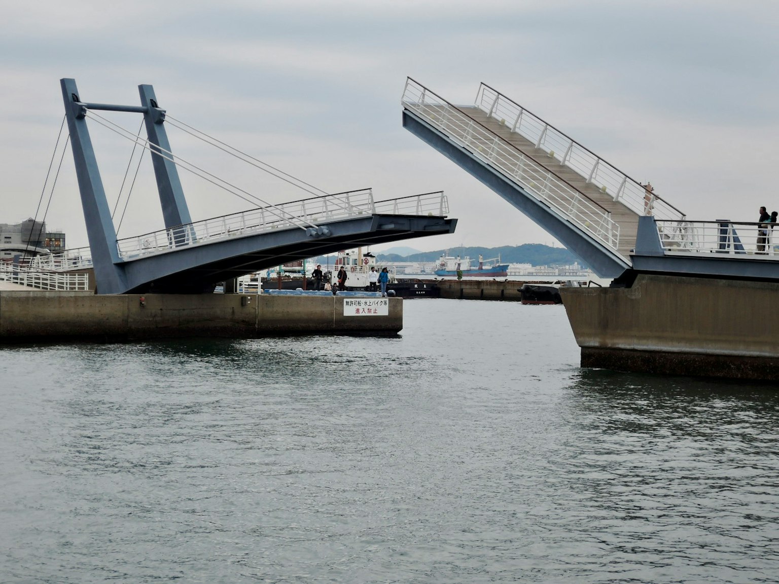A drawbridge tilting over water with people nearby