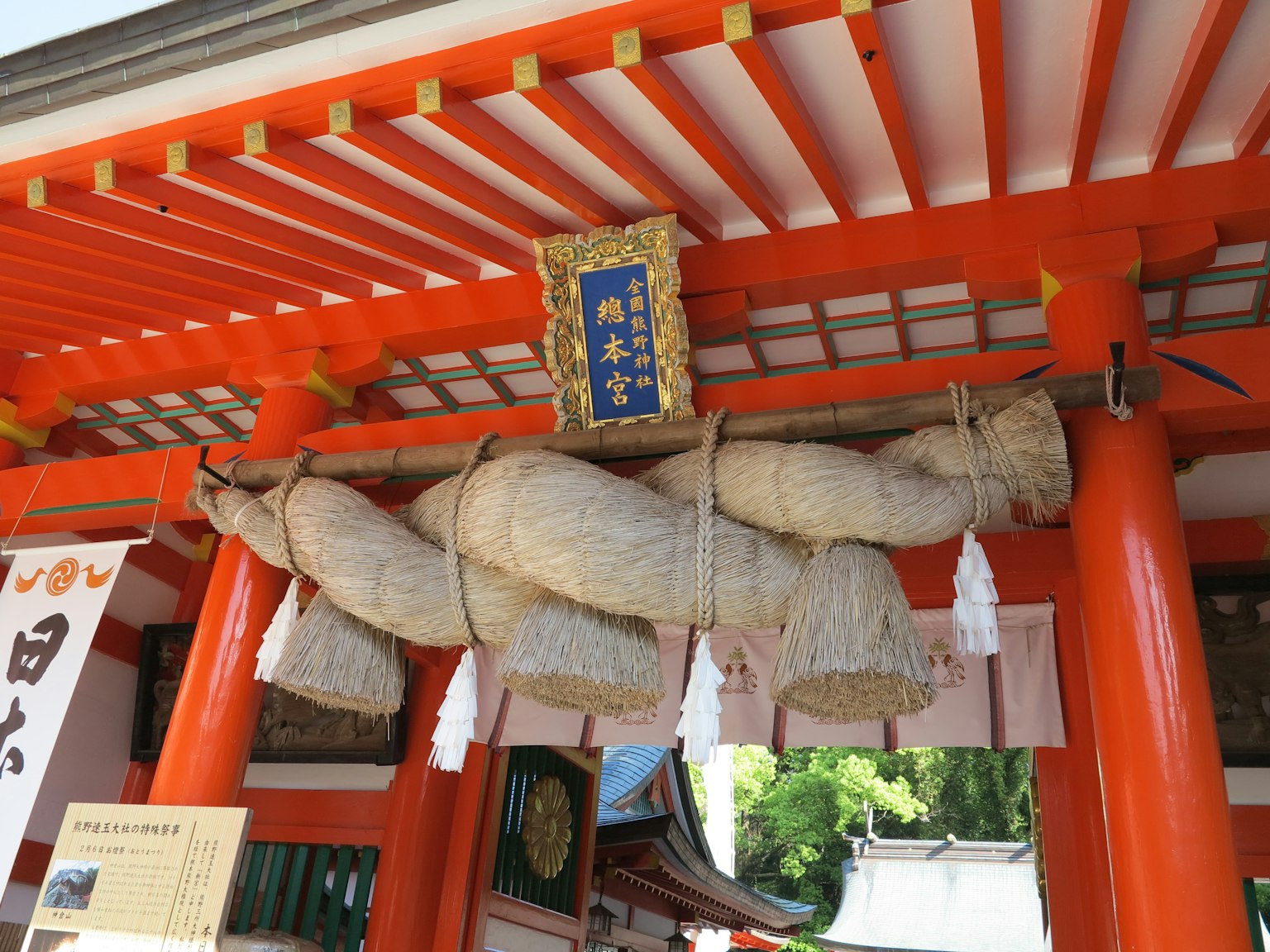Large straw rope hanging under a red torii gate with white shide