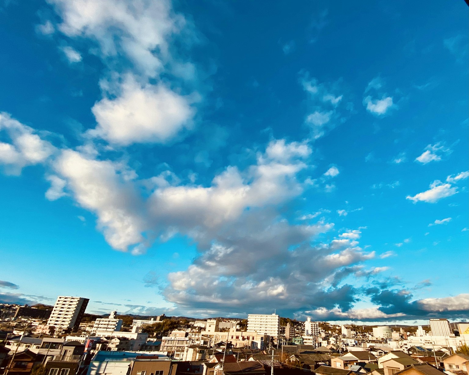 Cityscape with blue sky and white clouds featuring various buildings and residences