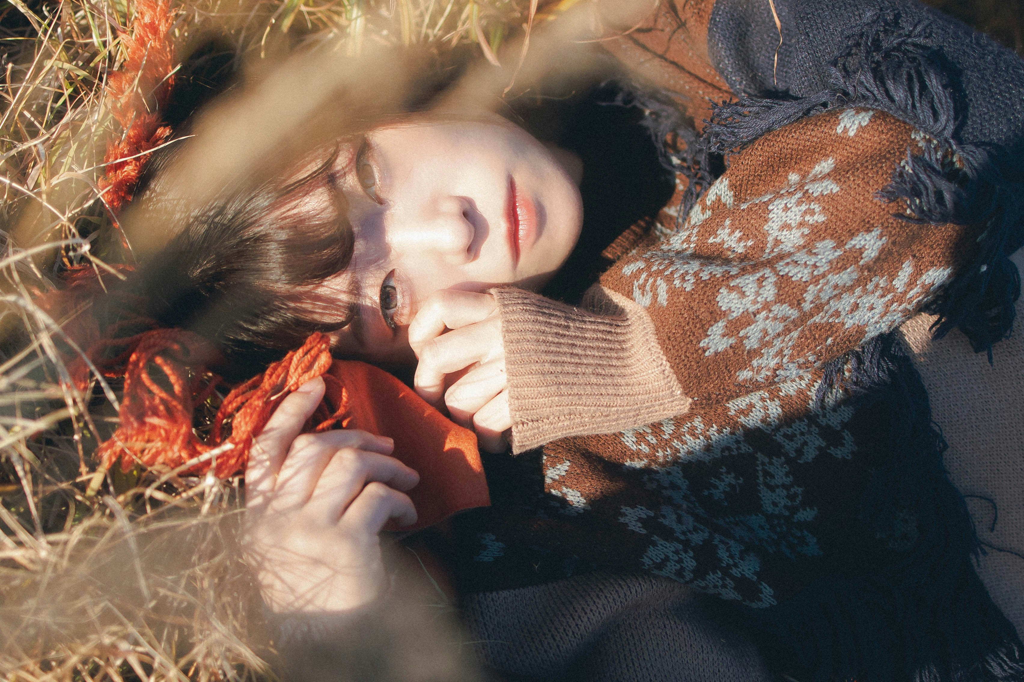 A parent and child cuddling wrapped in a blanket on grass