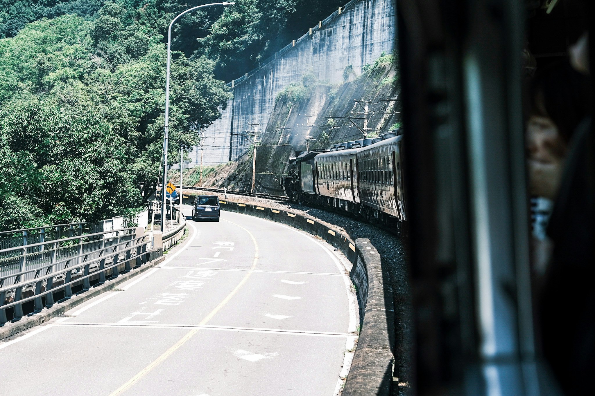 기차 창밖에서 본 산속 굽이진 도로 풍경