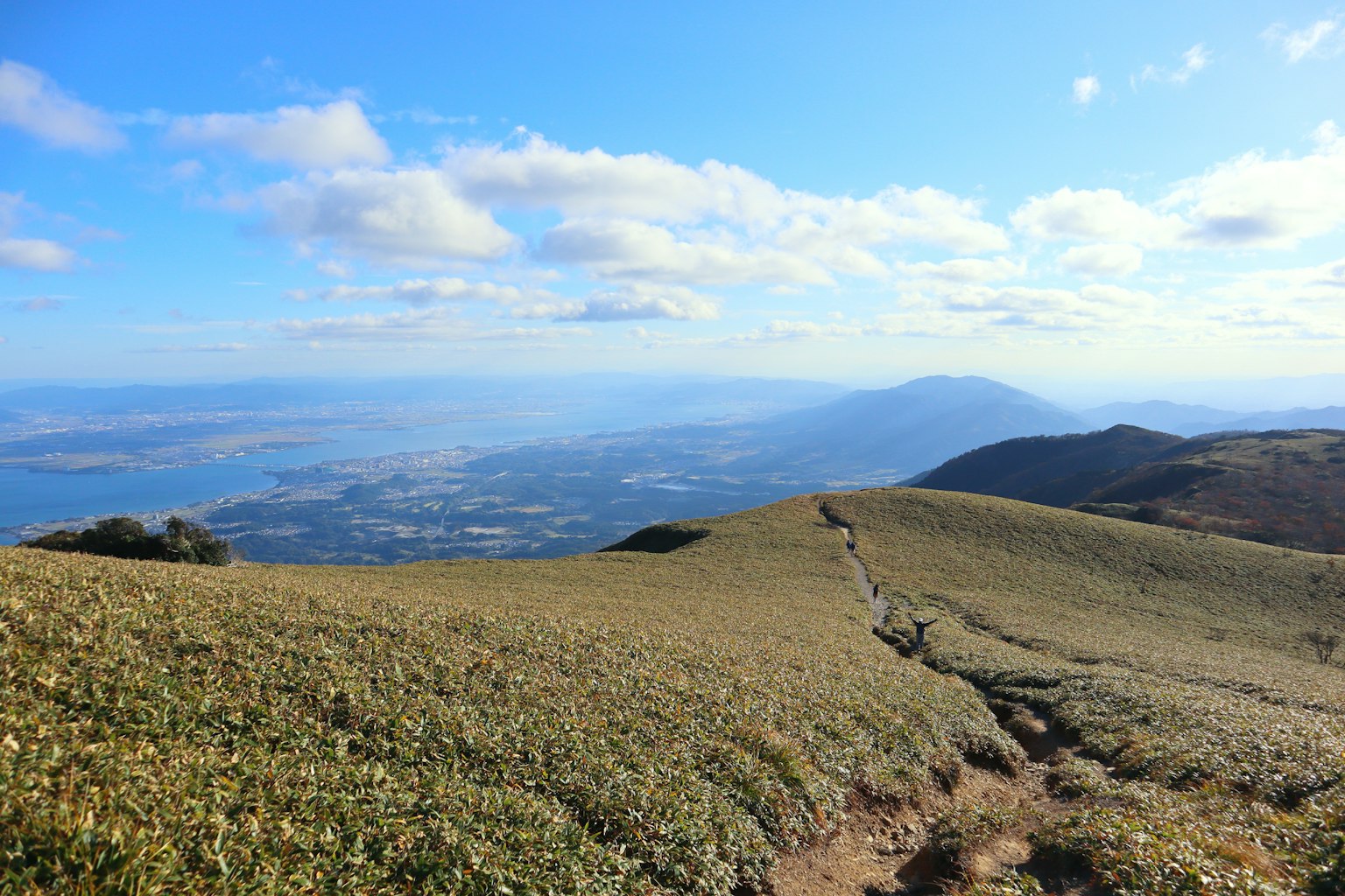 广阔的山地景观在蓝天和绿色草地下