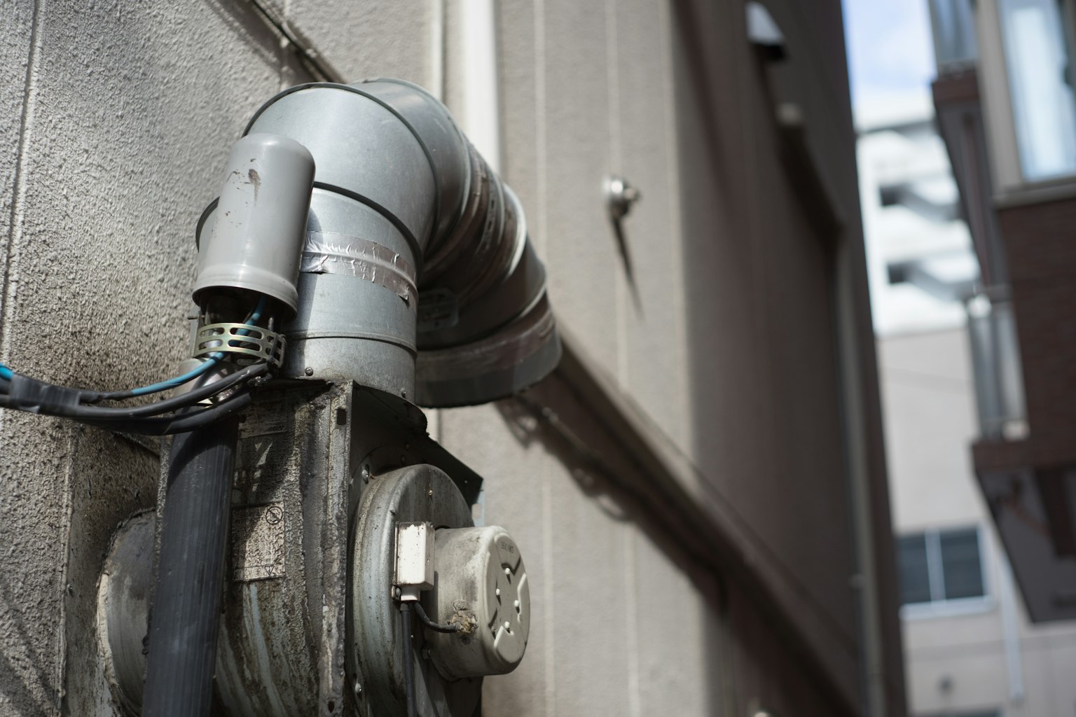Close-up of a gray pipe and cables mounted on a wall