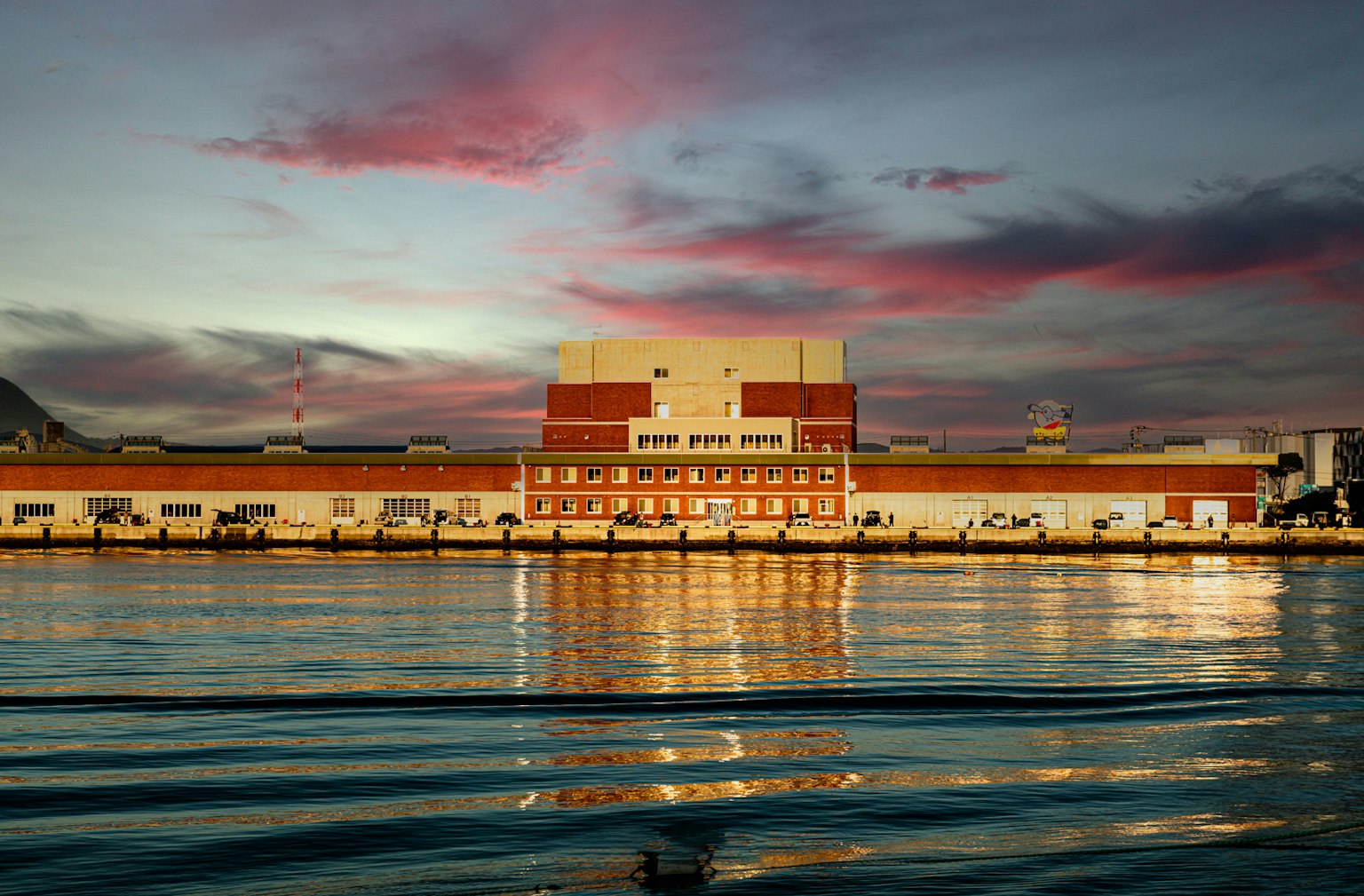 Bâtiment du port se reflétant sur l'eau sous un beau coucher de soleil