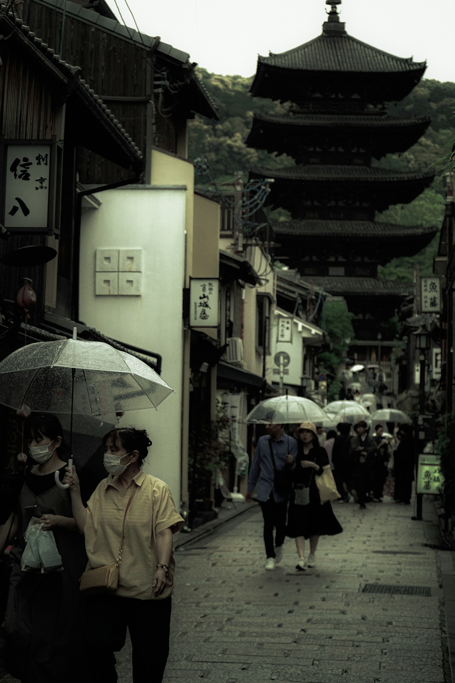 拿著雨傘的人在有塔樓的歷史街道上走