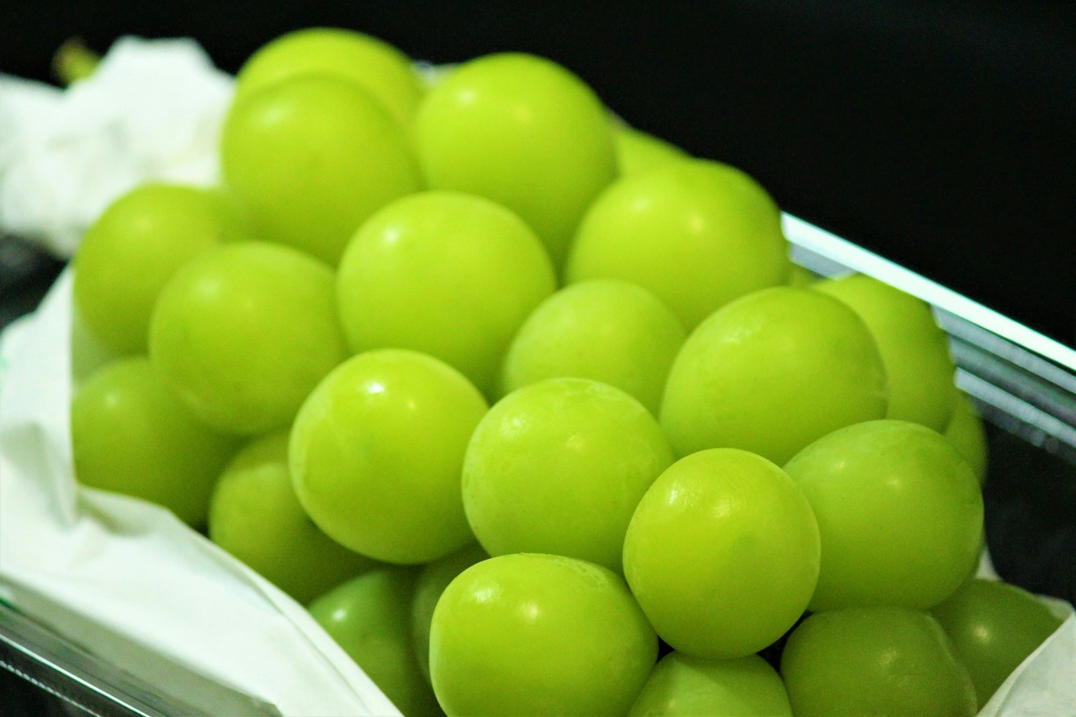 A cluster of green grapes resting on a white cloth