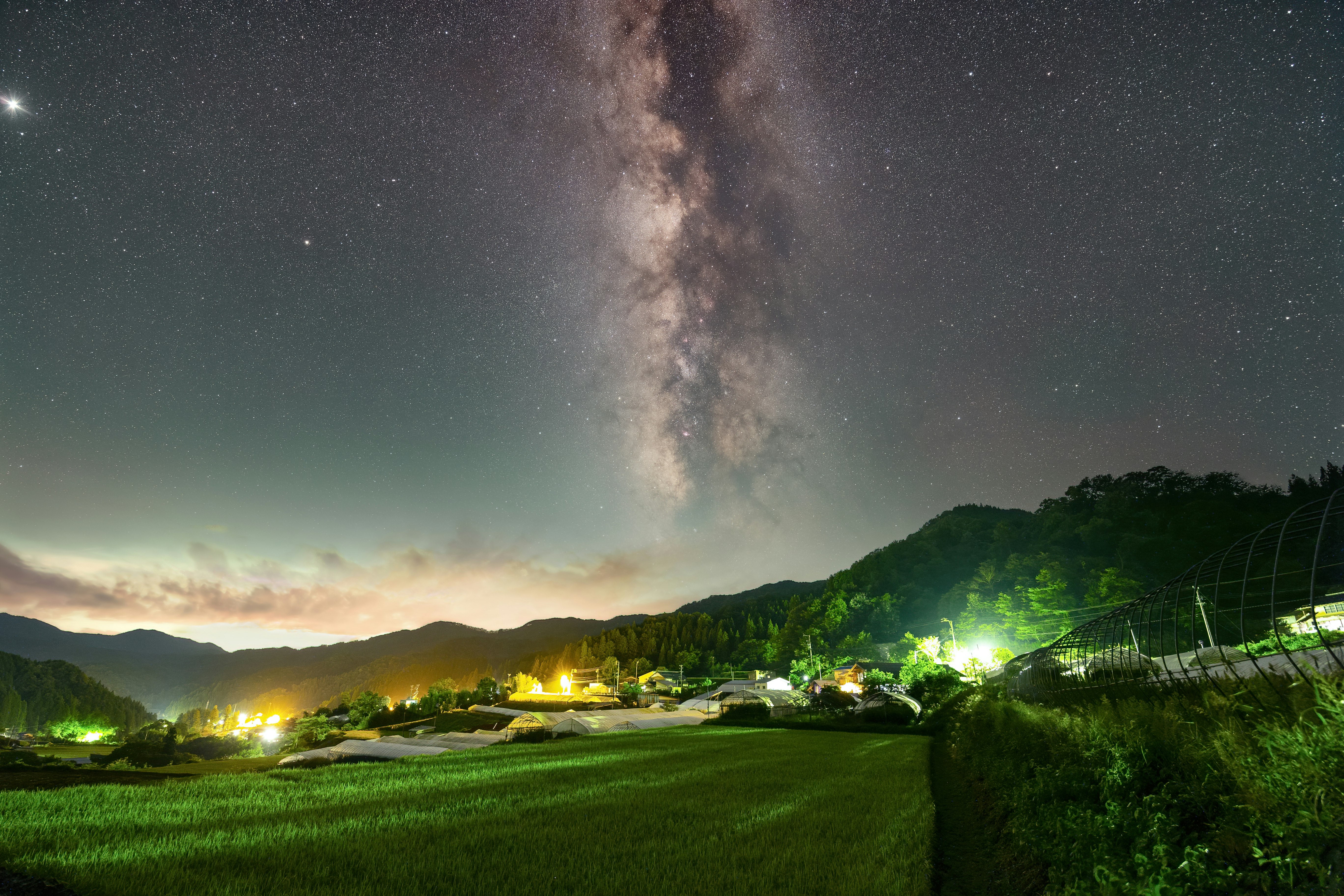 夜晚草地與山脈前的銀河星空