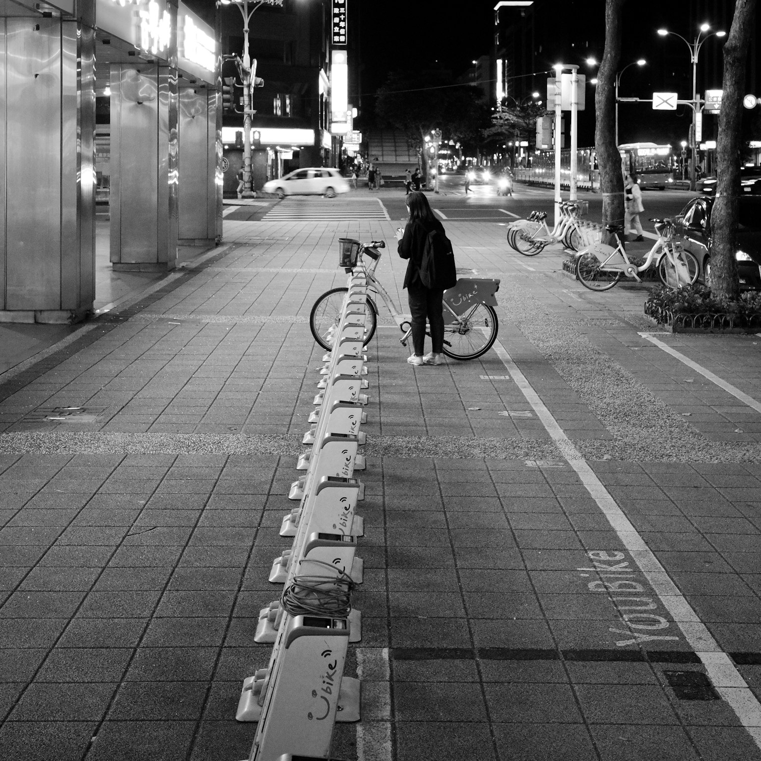Seseorang mendorong sepeda di kota di malam hari dengan lampu jalan