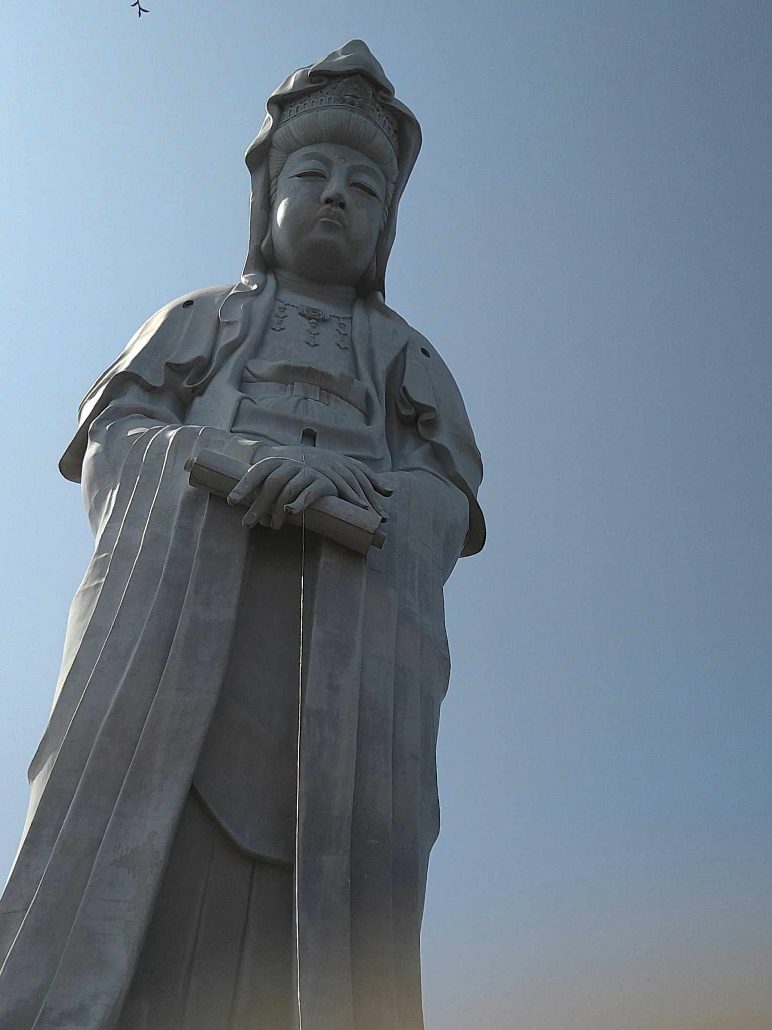 Una grande statua di Kannon si erge sotto un cielo blu