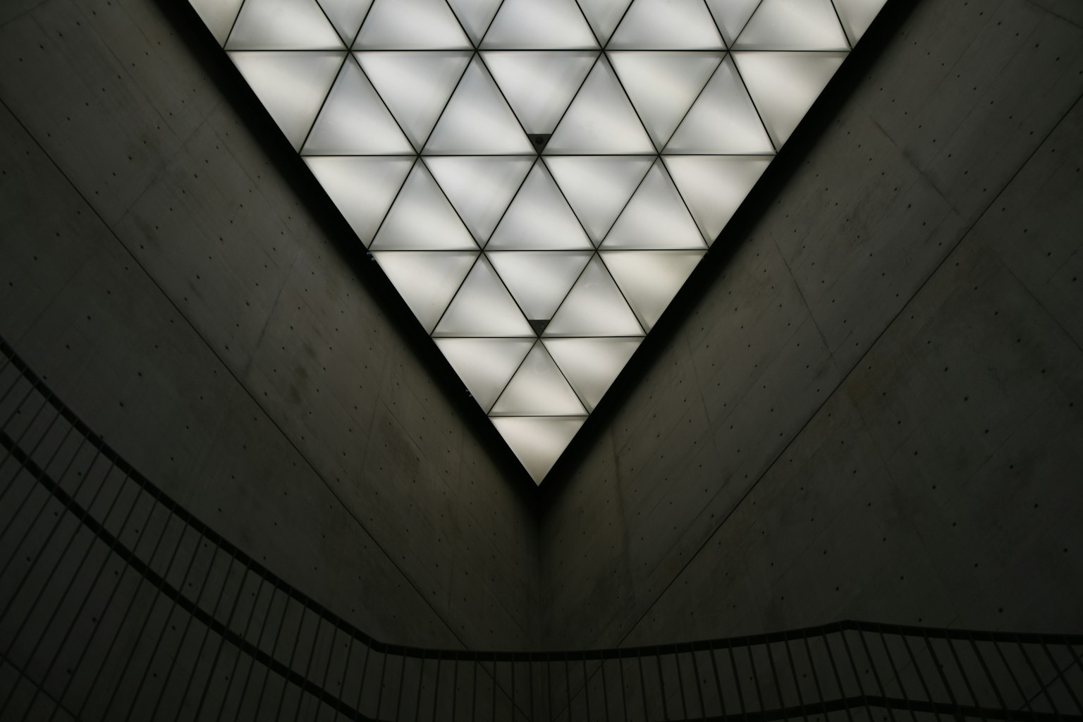 Vue intérieure d'un espace moderne avec un plafond triangulaire présentant des motifs géométriques illuminés