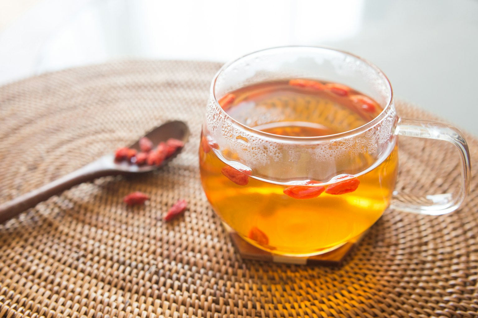 Tazza di vetro con tè alle bacche di goji e cucchiaio di legno