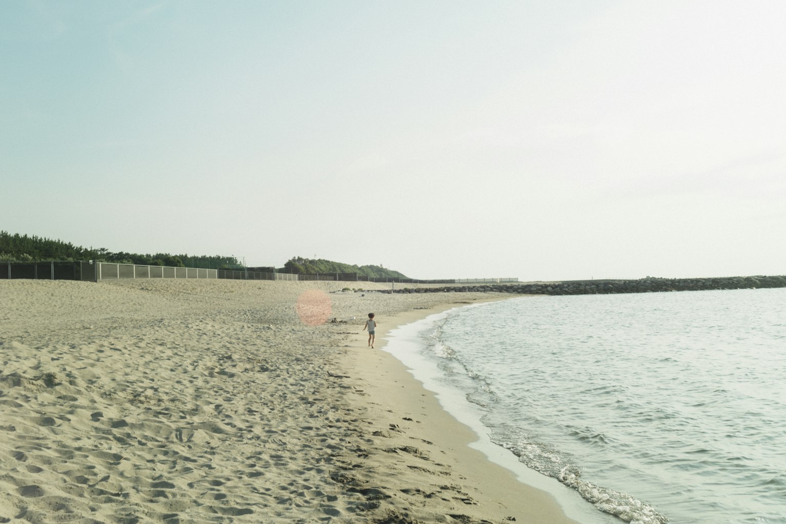 Niño caminando por una playa tranquila con olas suaves