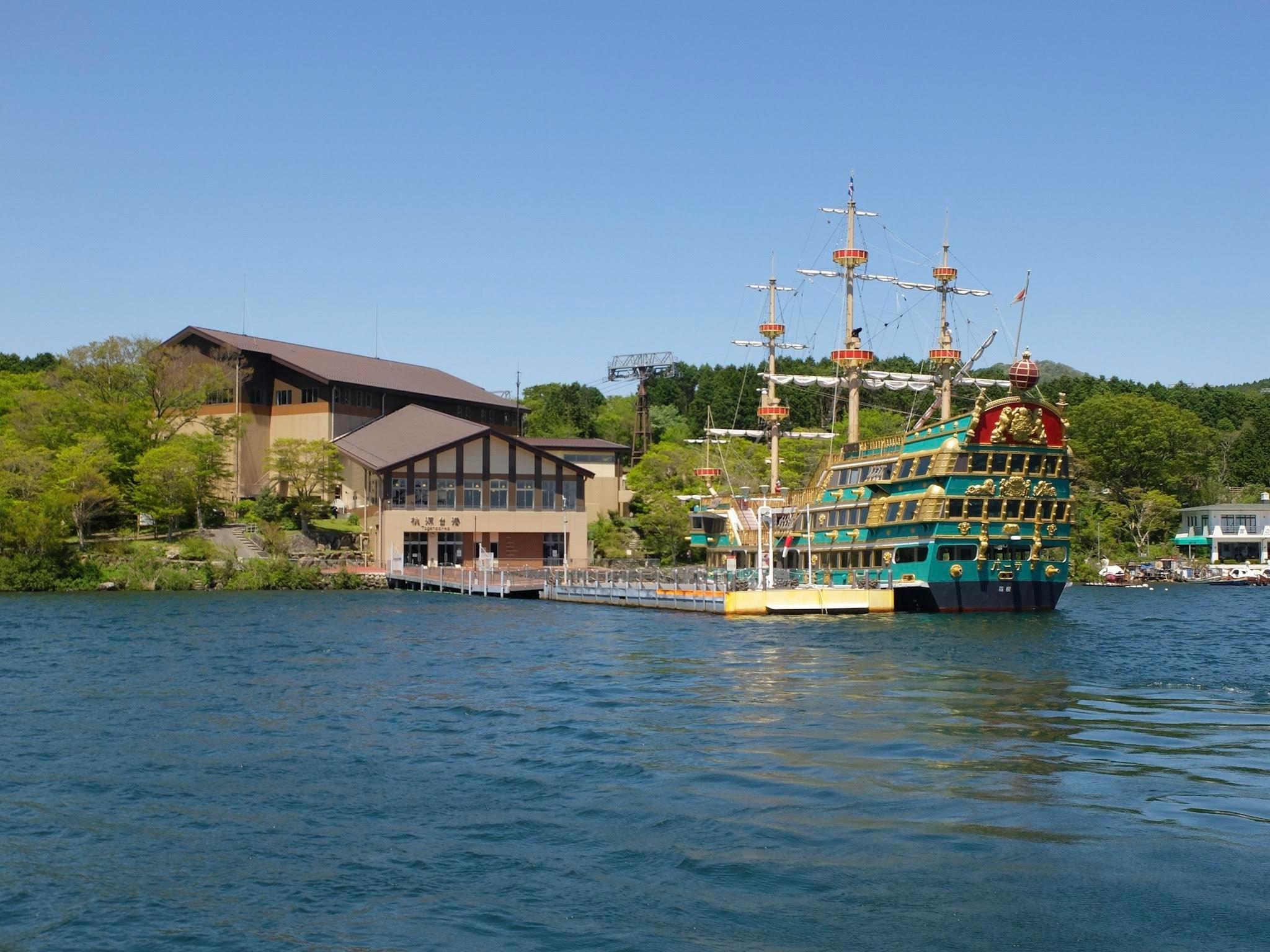 large ship sailing along a river with moored vessels