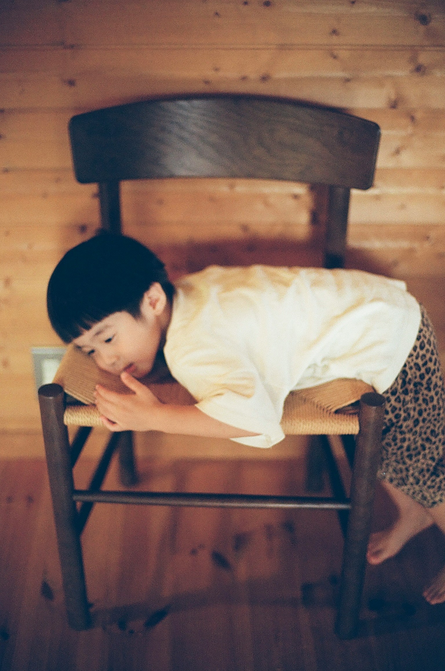 เด็กนอนอยู่บนเก้าอี้ไม้ในบรรยากาศที่อบอุ่น