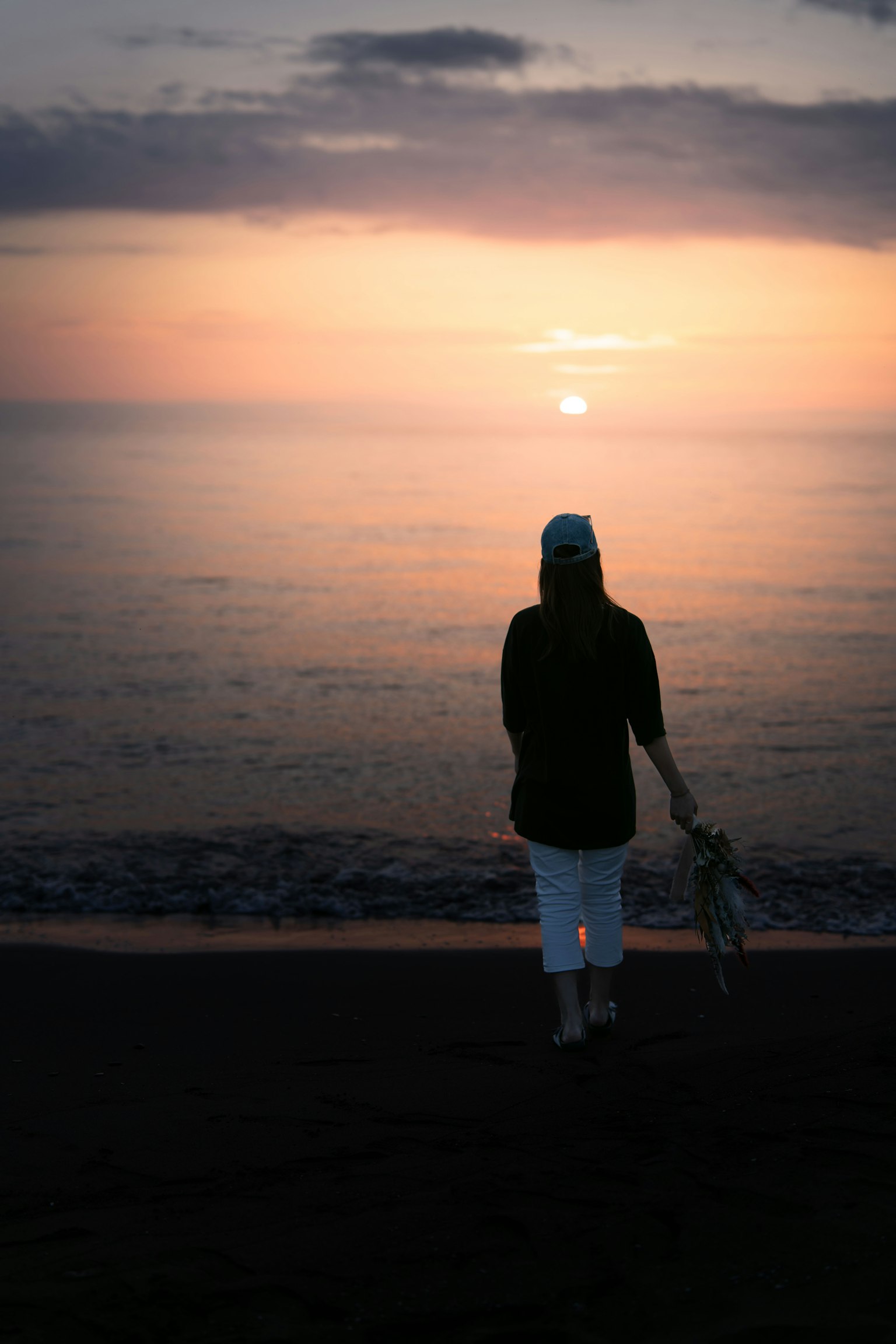 Woman walking along the beach at sunset