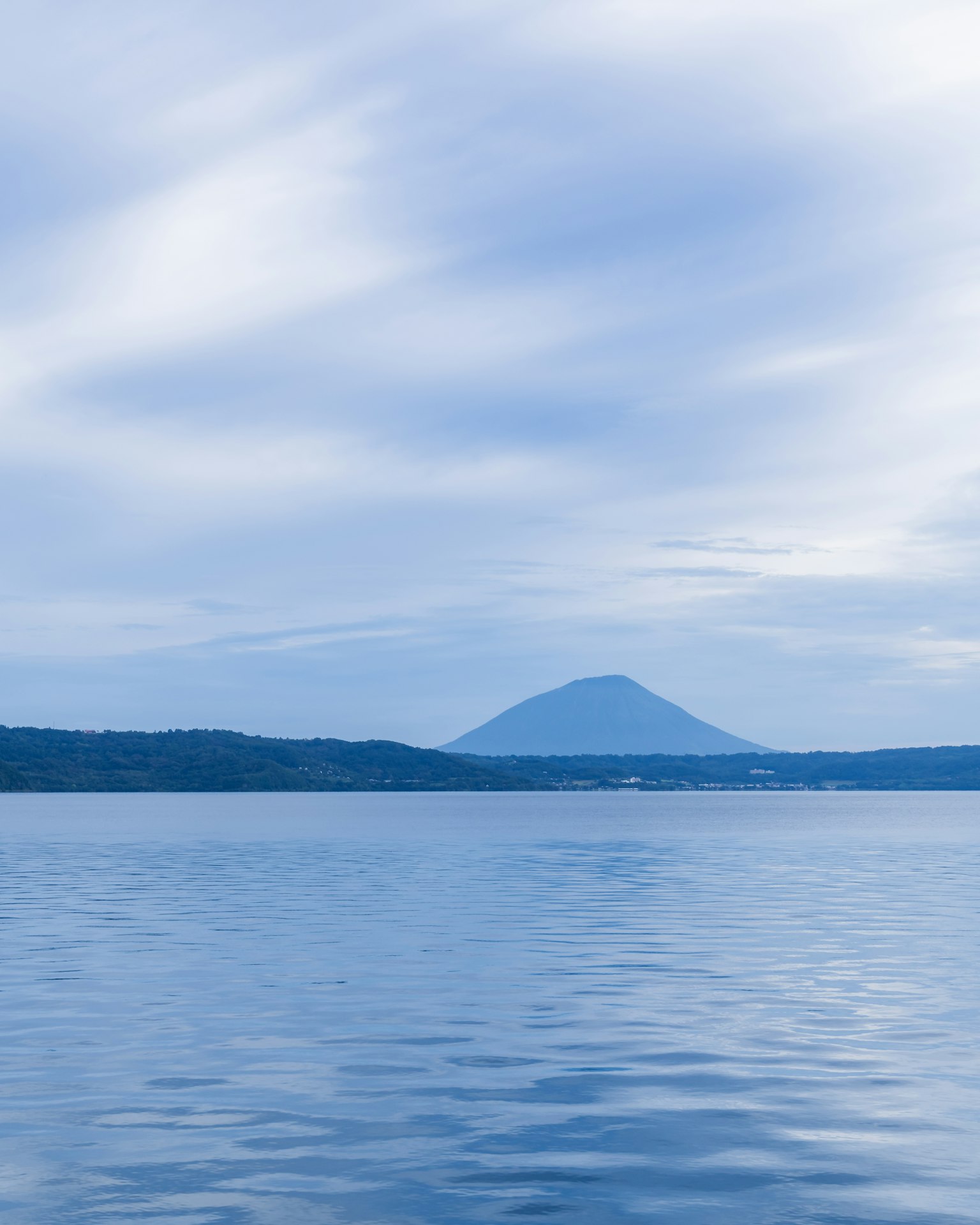 Ruhige Seefläche unter einem blauen Himmel mit einem Berg im Hintergrund