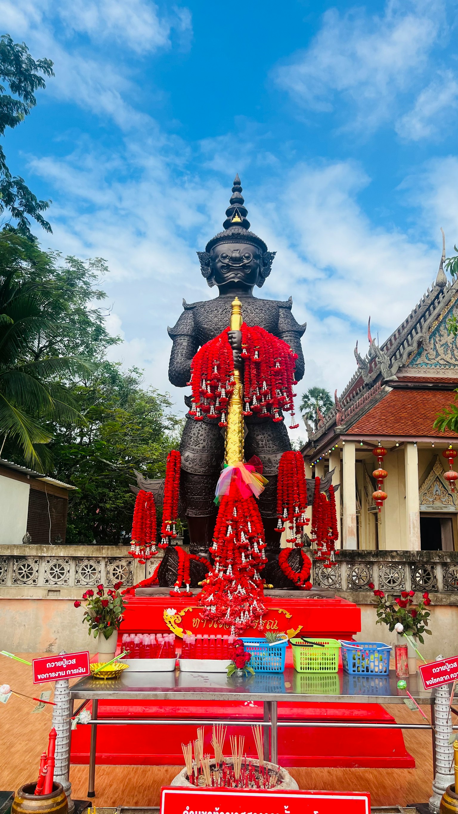 Una gran estatua negra adornada con decoraciones rojas en un entorno de templo