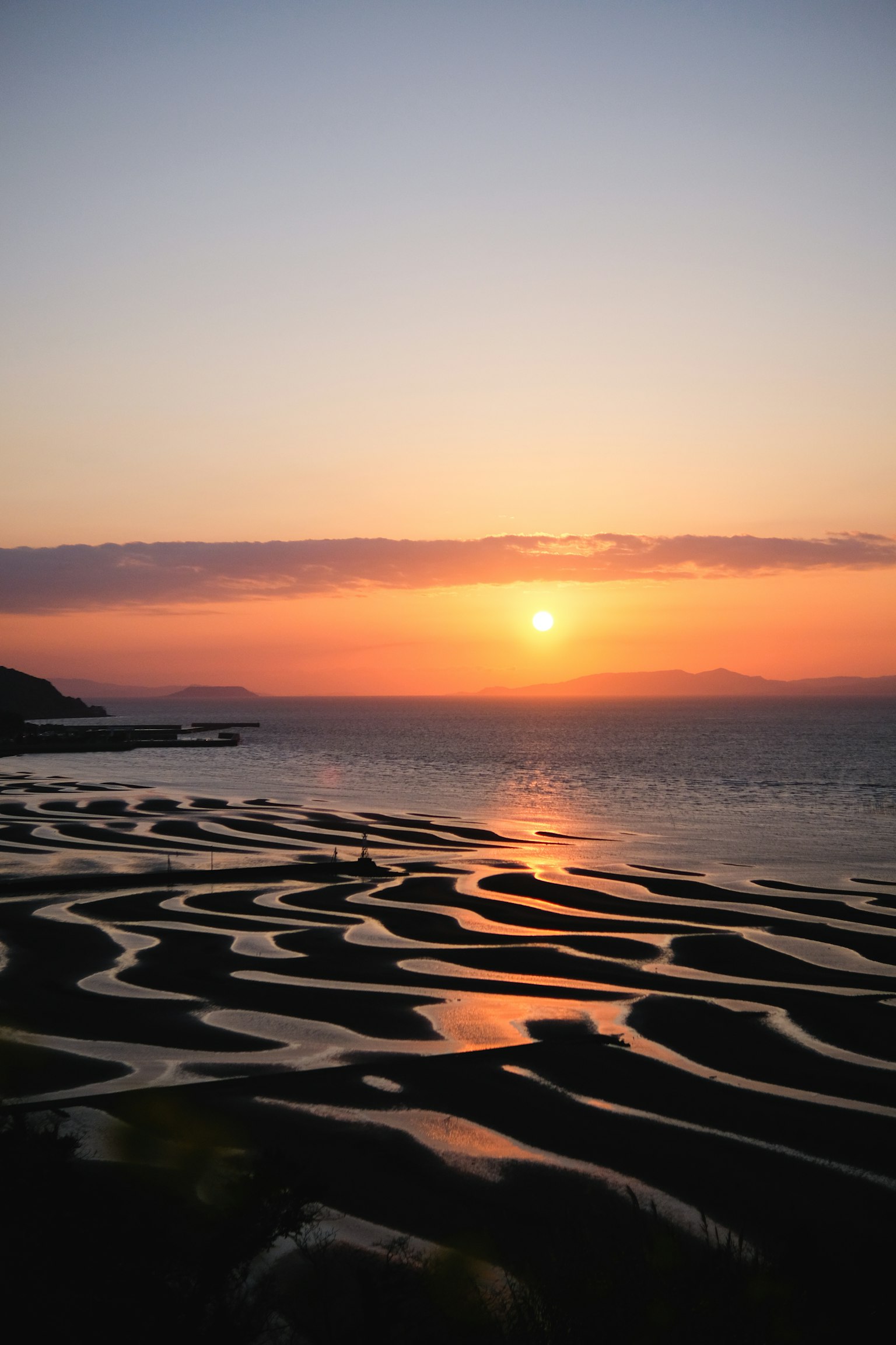 Wunderschöne Küstenlandschaft mit Sonnenuntergang, der sich auf terrassierten Reisfeldern spiegelt