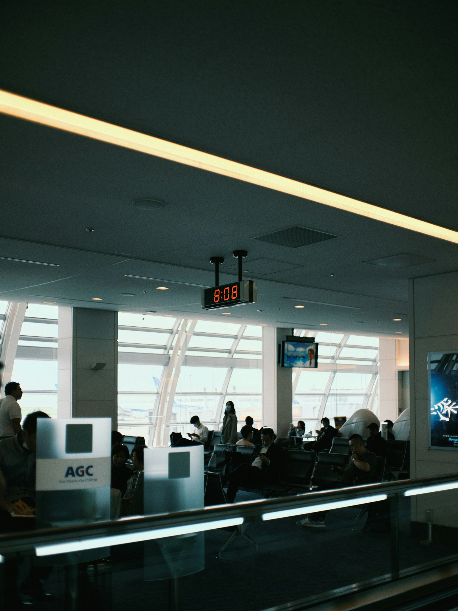 Photo of travelers in an airport waiting area with a visible clock
