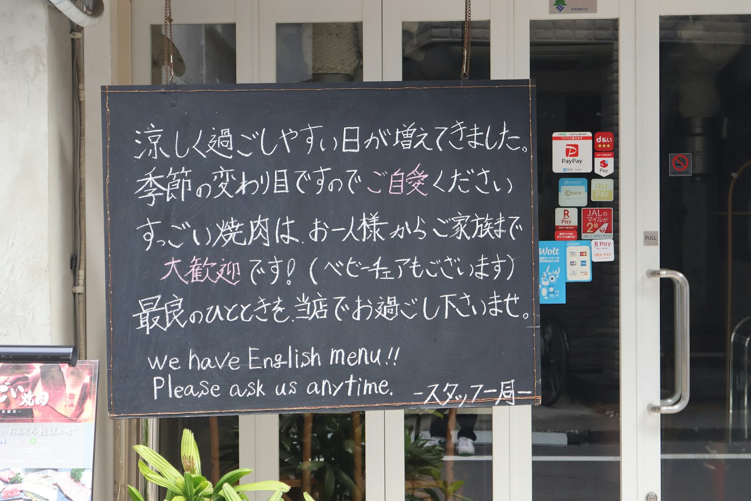 黒板に書かれたメニューと英語の案内がある飲食店の入り口