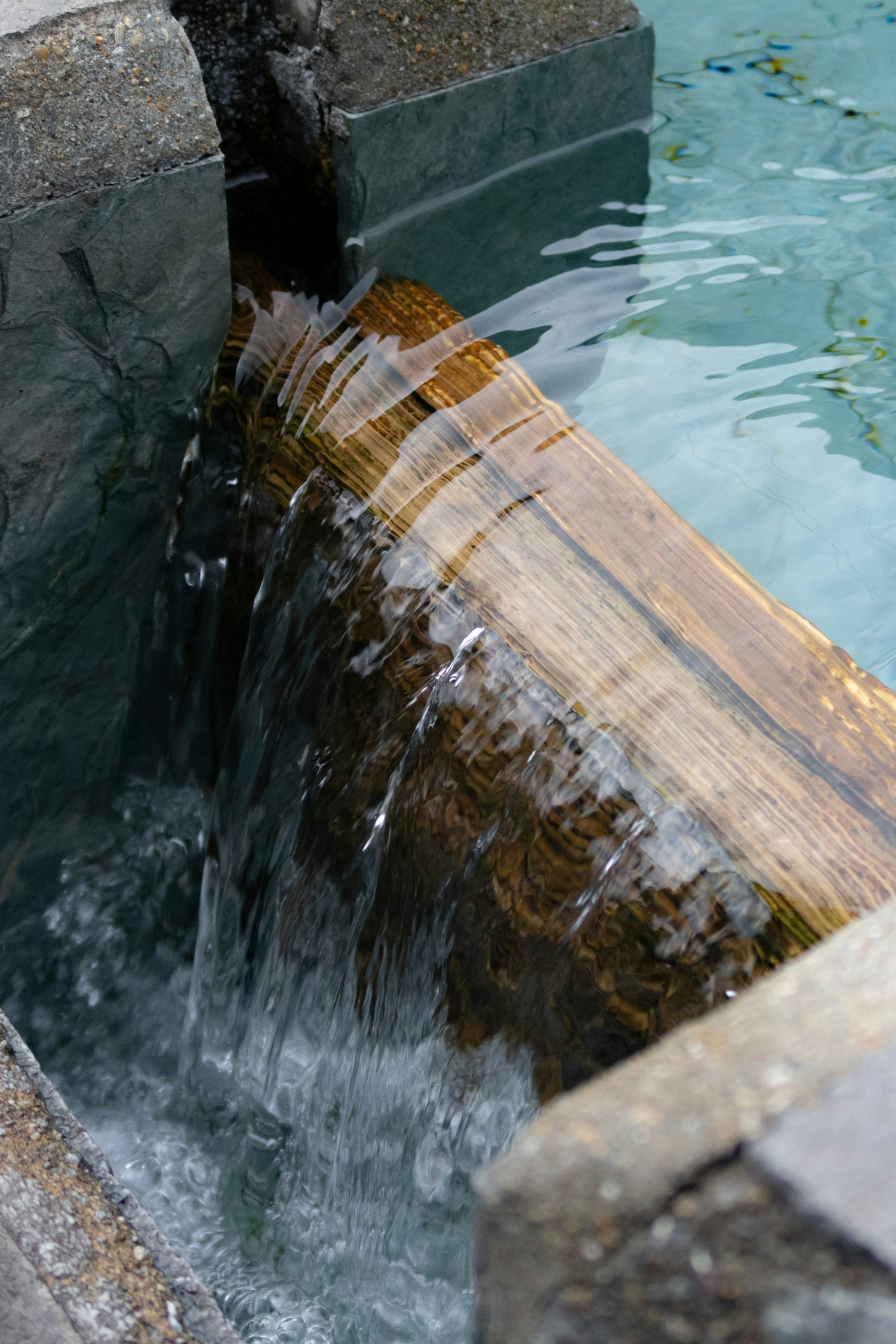 Elemento d'acqua in legno con acqua che scorre e struttura in pietra