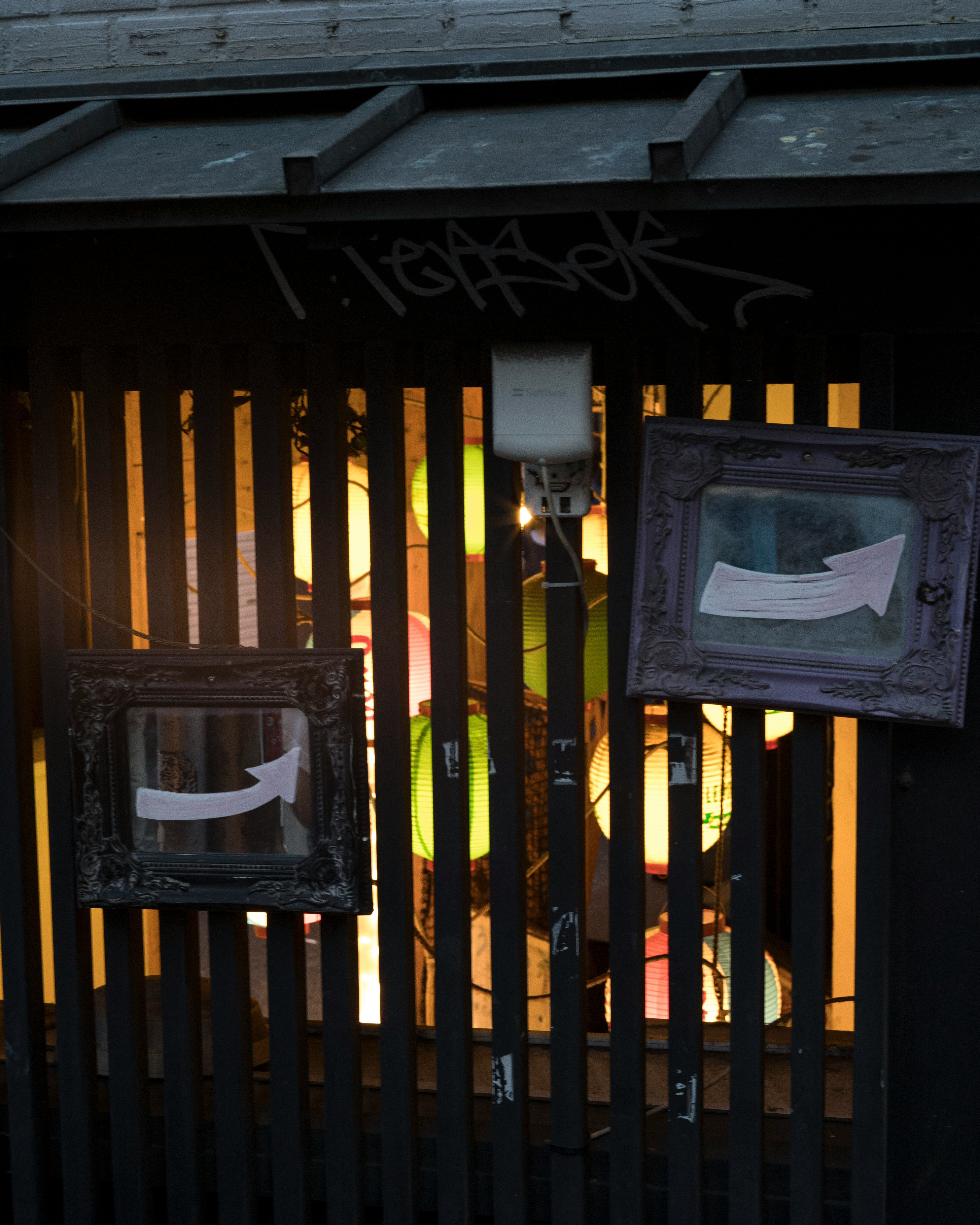 Warm lights glowing behind a wooden slat fence with hanging papers