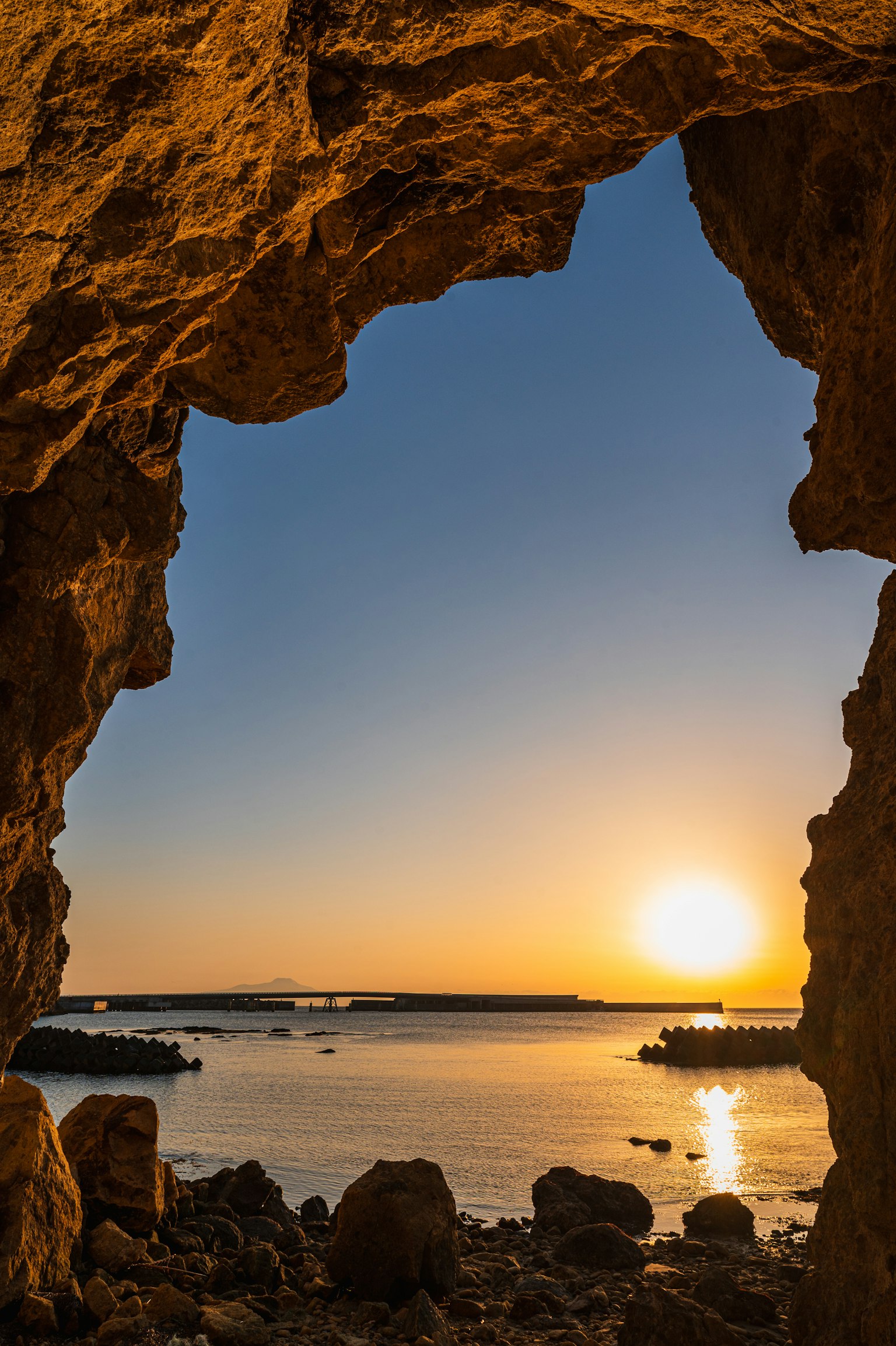 Vista del tramonto e dell'oceano attraverso un arco di roccia
