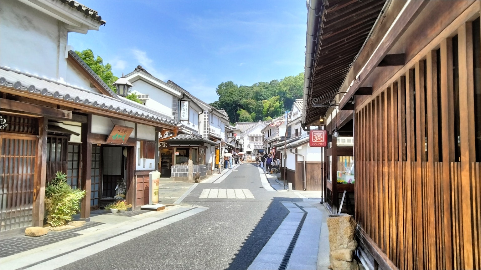 Traditional buildings lining a narrow street with green hills